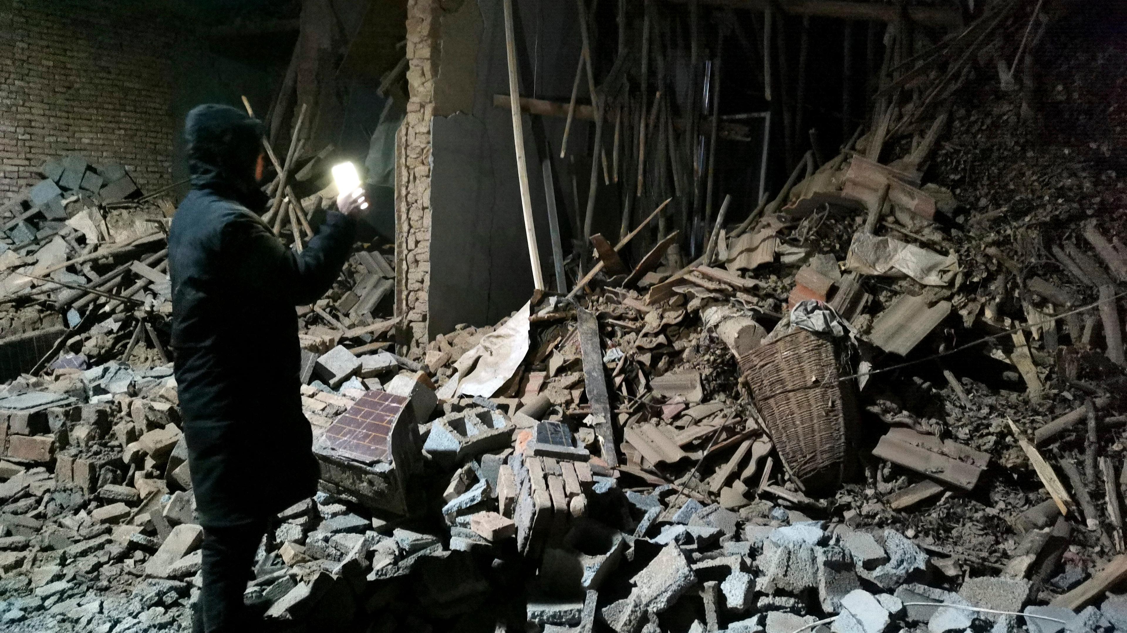Ein Mann steht vor den Trümmern eines eingestürzten Hauses