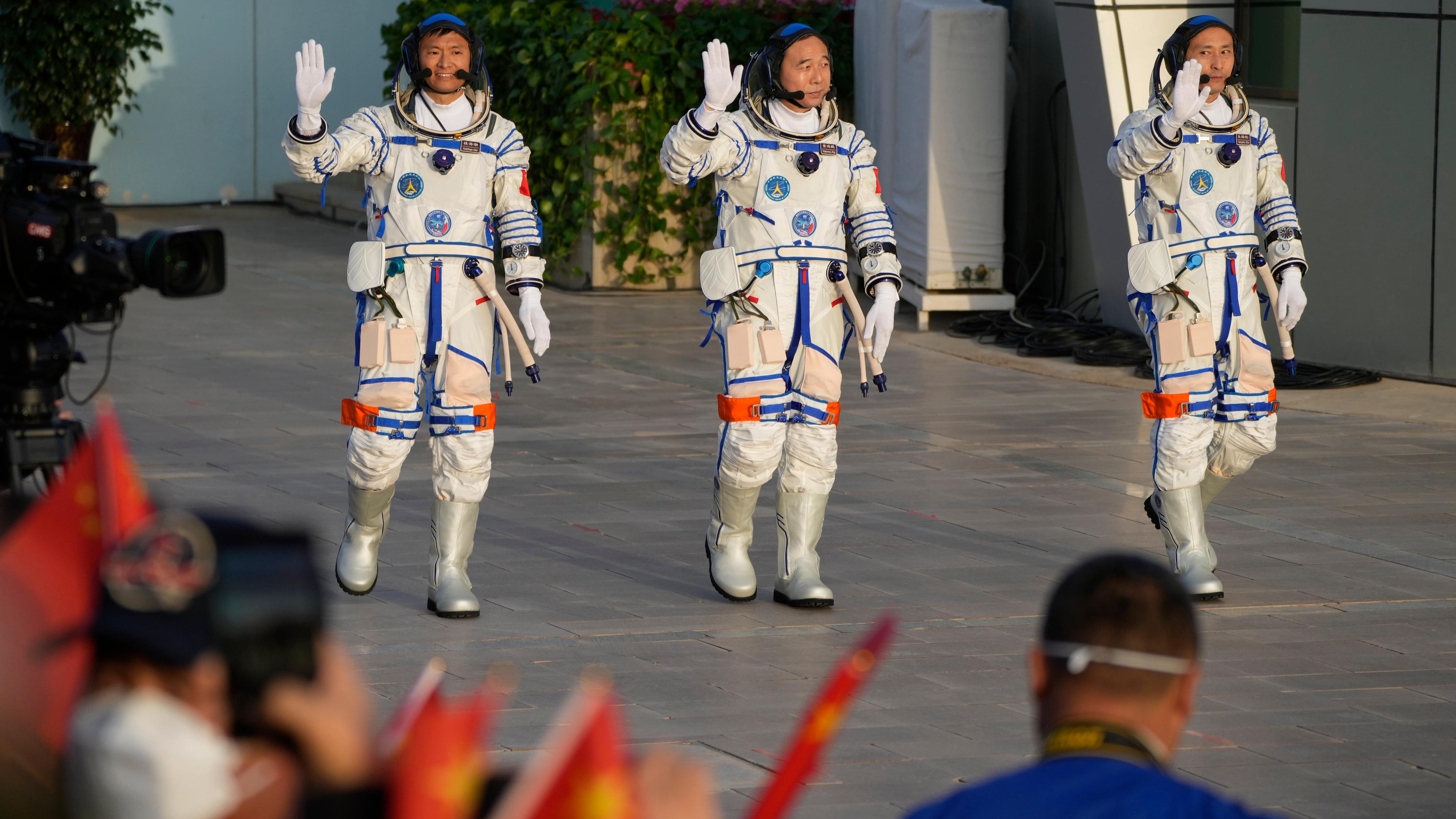 Drei chinesische Astronauten winken bei der Begrüßungzeremonie bevor dem Start der Raumfahrtmission.