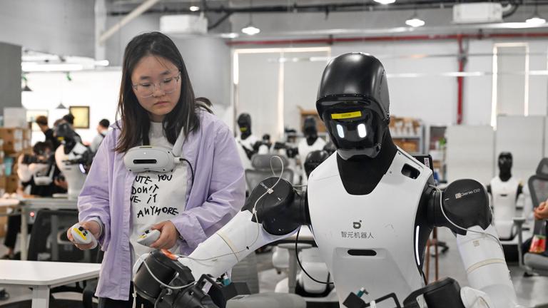 Mitarbeiter trainiert einen Roboter an einer Produktionslinie in Shanghai, China.