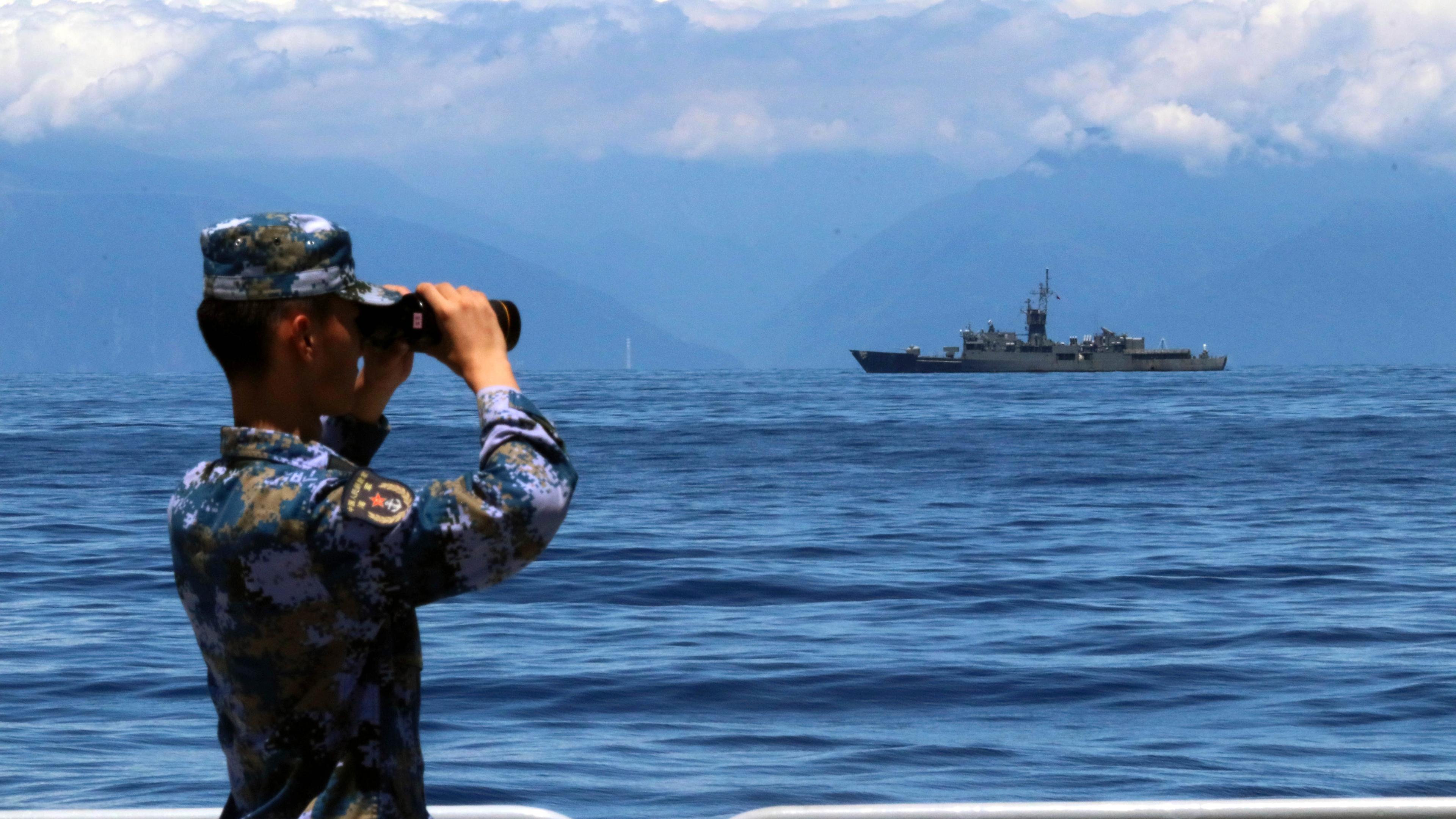 Das von der chinesischen Nachrichtenagentur Xinhua veröffentlichte Foto zeigt eine Mitglied der chinesischen Volksbefreiungsarmee, der während einer Militärübung auf See durch ein Fernglas guckt während im Hintergrund Taiwans Fregatte Lan Yang zu sehen ist.