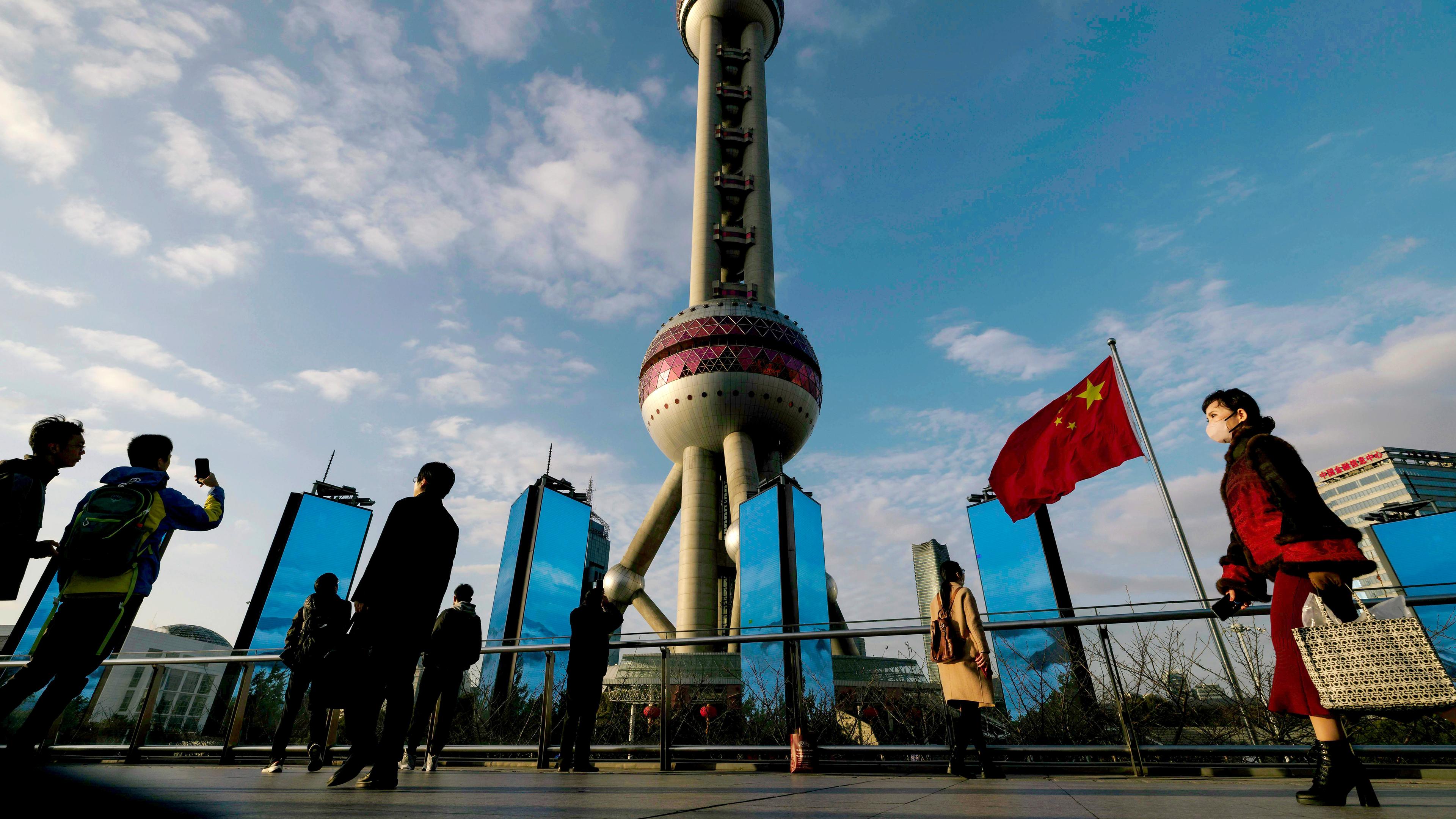 Menschen gehen unter dem Oriental Pearl Tower im Finanzzentrum Liuiazui in Shanghai