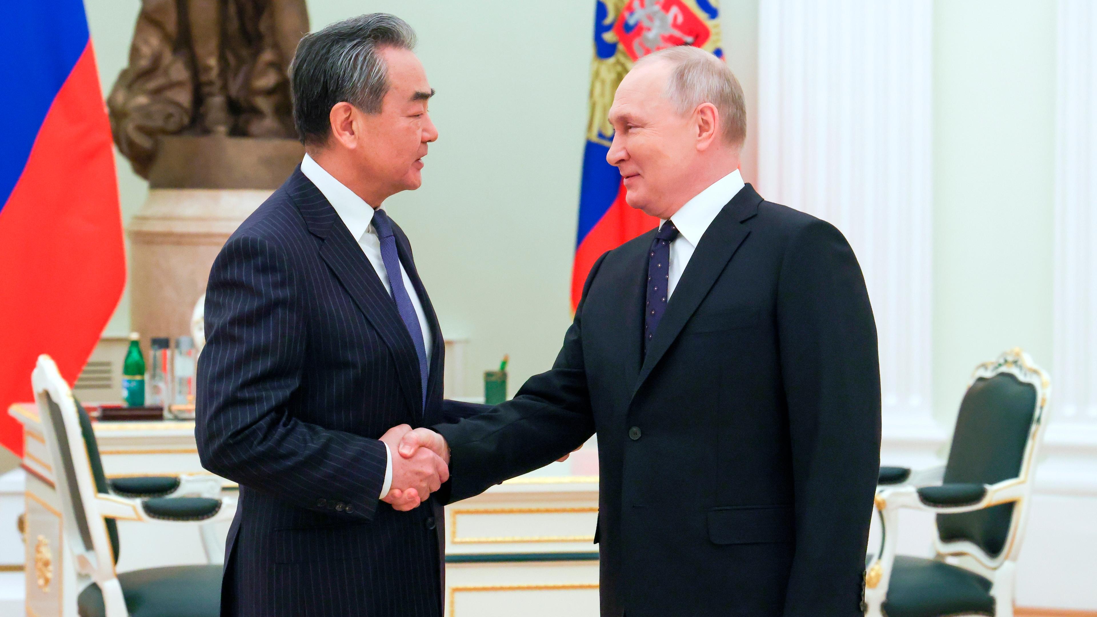 Chinas Chef-Außenpolitiker Wang Yi und der russische Präsident Wladimir Putin beim Handschlag.