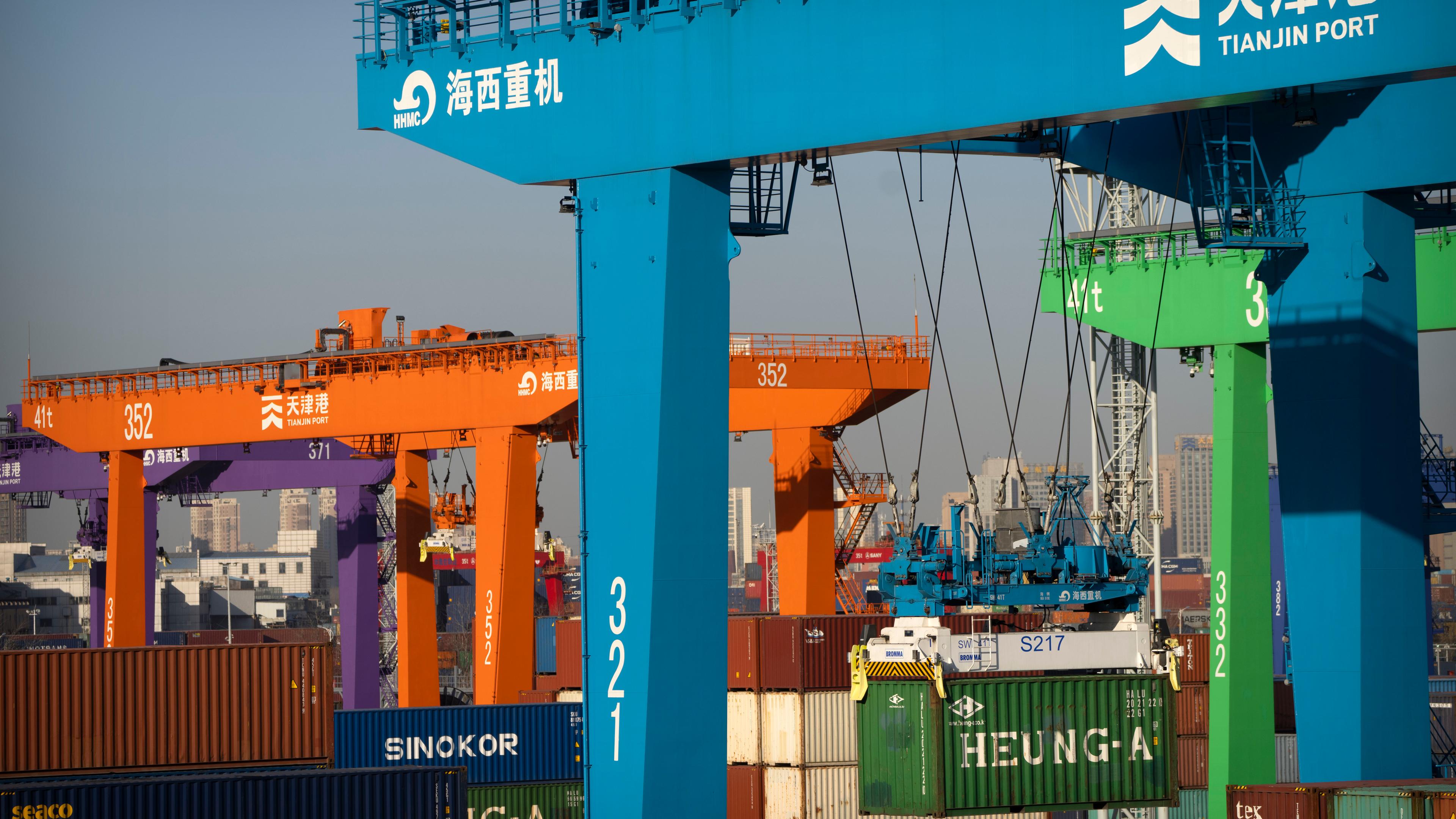 Ein Kran hebt einen Schiffscontainer in einem automatisierten Containerhafen in Tianjin