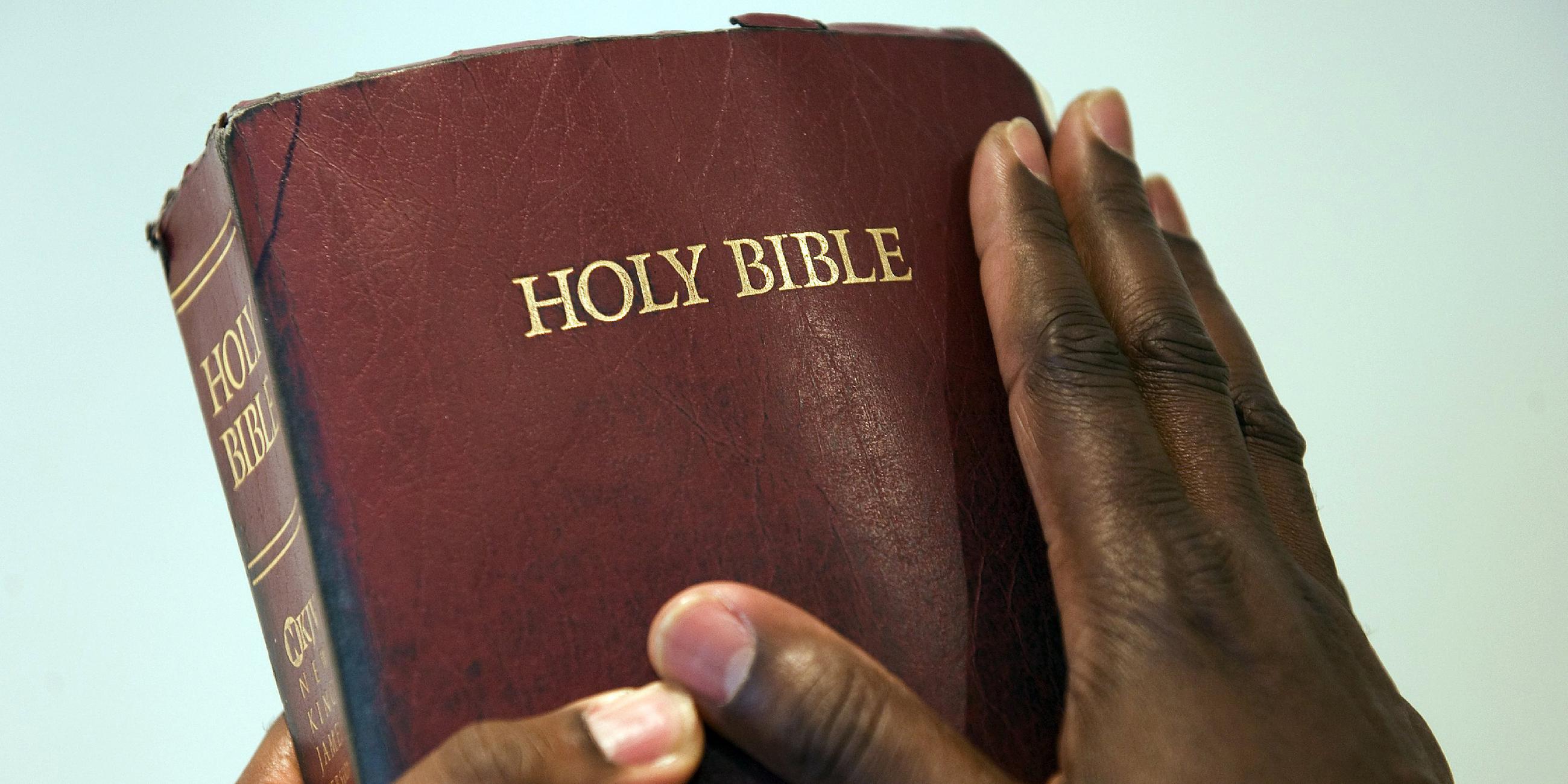 Hände eines afrikanischen Mannes halten eine Bibel