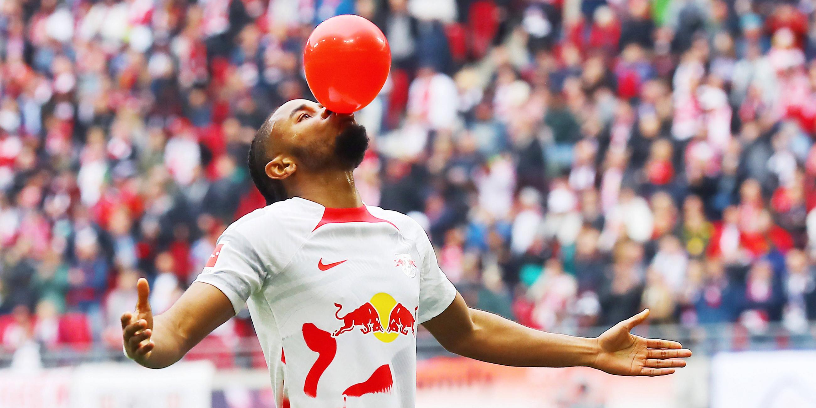 Christopher Nkunku (RB Leipzig) bejubelt sein Tor mit einem rotem Luftballon im Mund