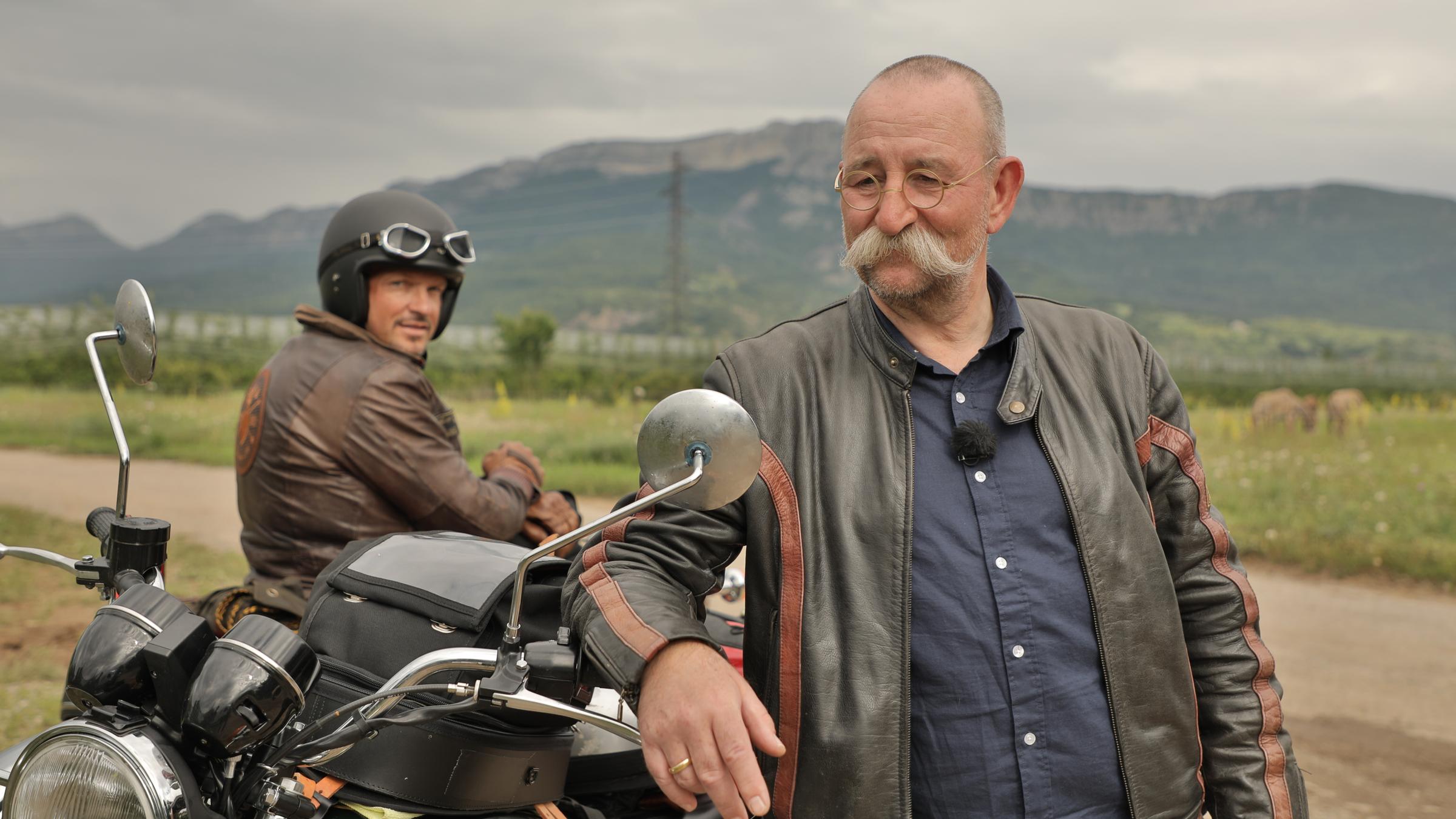 "Horst Lichter sucht das Glück": Horst Lichter  steht im Bildvordergrund mit geöffneter Motorradjacke neben seinem Motorrad und stützt sich mit dem rechten Unterarm auf den Lenker. Im Hintergrund sitzt Hardy Krüger auf seinem Motorrad. Er trägt einen Helm und schaut in die Kamera.