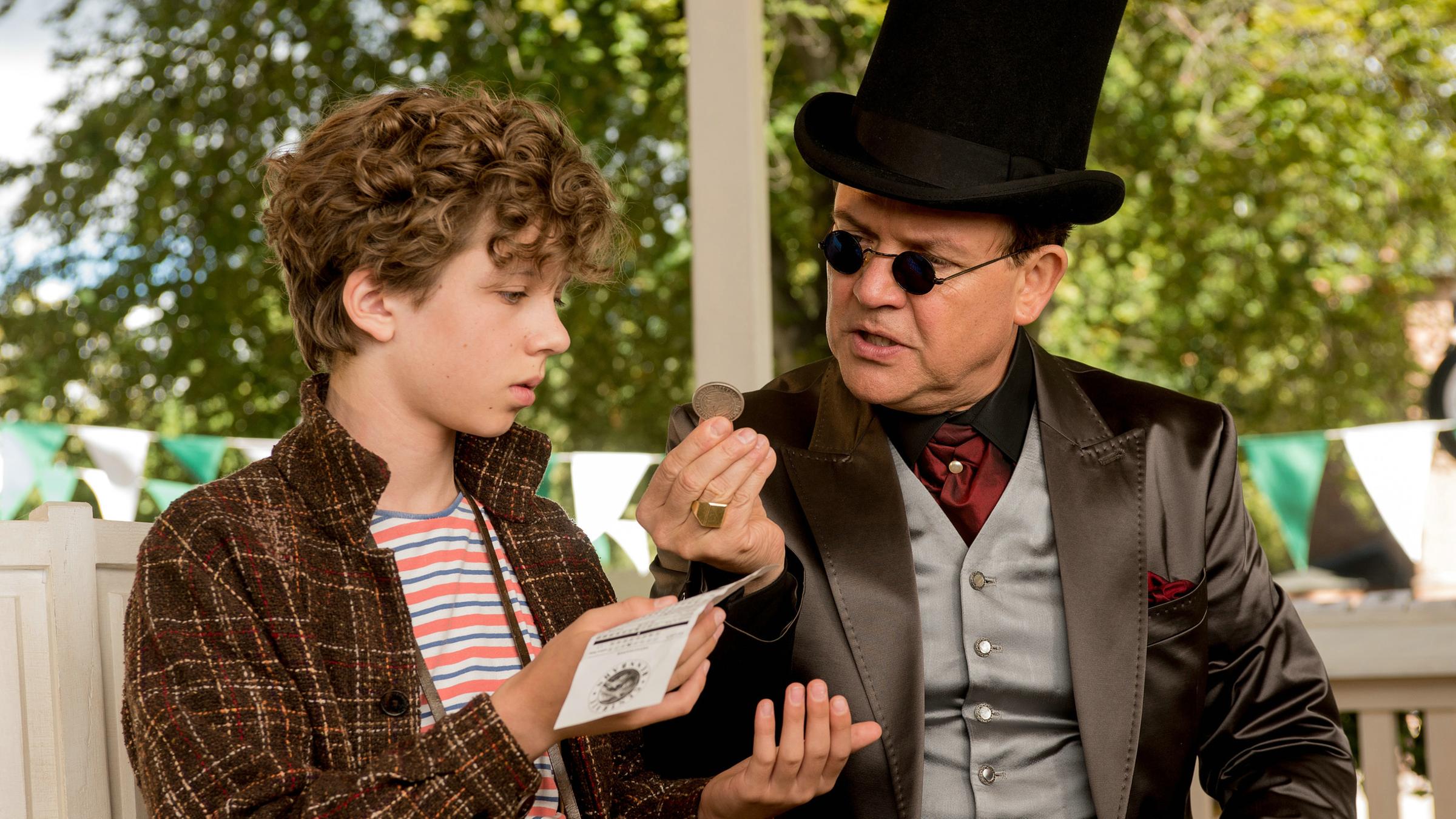 "Timm Thaler oder das verkaufte Lachen": Baron Lefuet (Justus von Dohnányi) und Timm (Arved Friese) sitzen auf einer Parkbank. Der Baron zeigt Timm eine Münze, die dieser entgegen nimmt. In der anderen Hand hält Timm einen Wettschein.