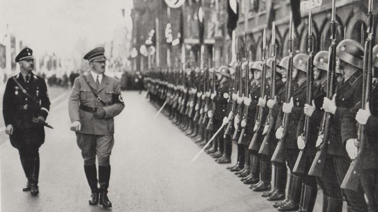 "Der Zweite Weltkrieg: Die Welt am Abgrund": Schwarz-Weiß-Aufnahme: Adolf Hitler schreitet, gefolgt von Heinrich Himmler, an einer Reihe angetretener Soldaten vorbei.