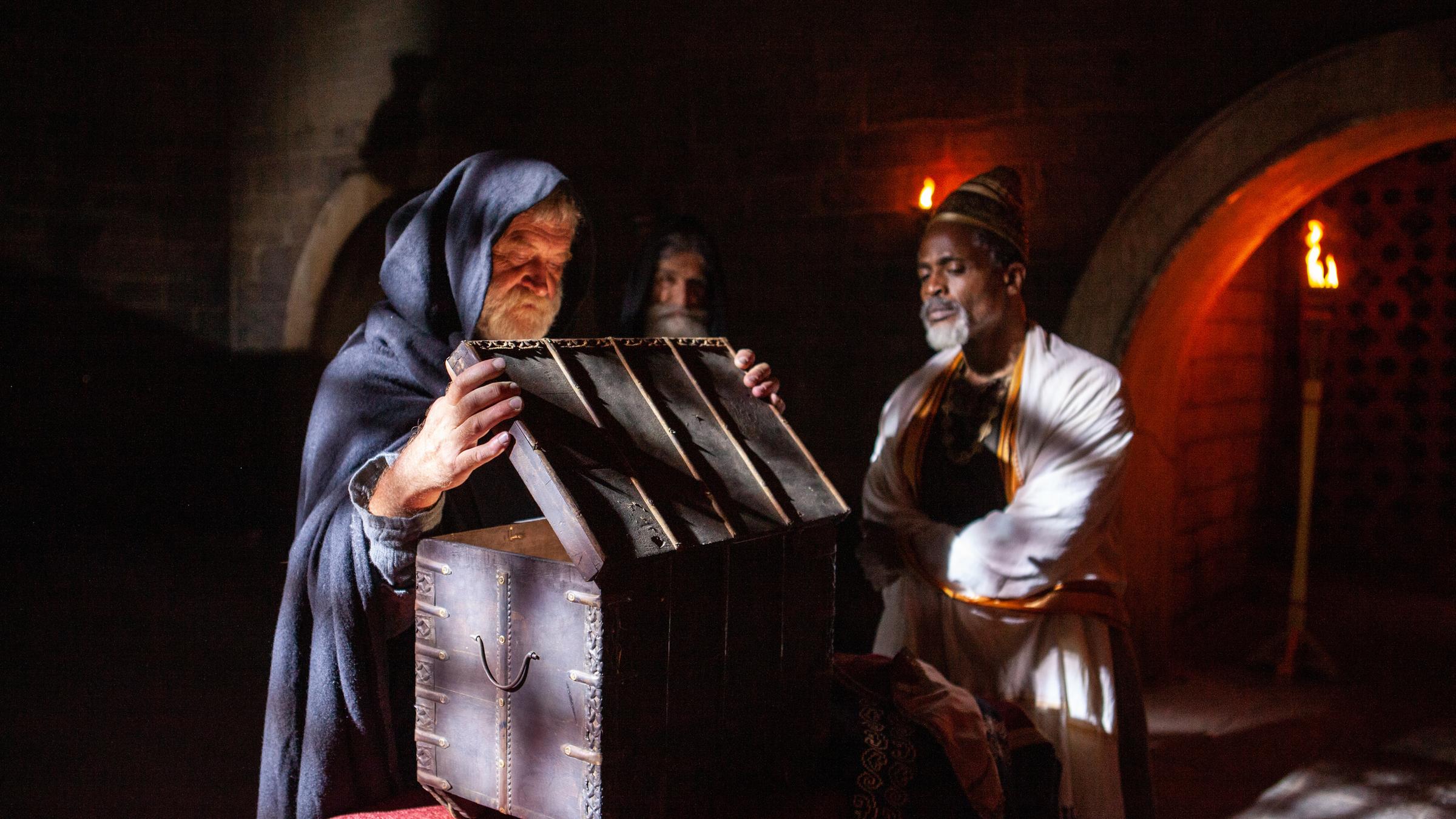 "Terra X: Tabu - Verbotene Orte": Spielszene: Der Mönch Dimotheus (Graham Weir) öffnet die Bundeslade. Beobachtet wird er dabei von Mönch Isaak (Chris Steyn) und Prinz Kassa (Courtney Michael).