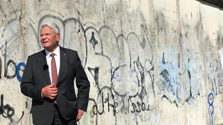 "ZDFzeit: 30 Jahre Mauerfall - Joachim Gaucks Suche nach der Einheit": Joachim Gauck steht vor den Resten der Mauer in Berlin.