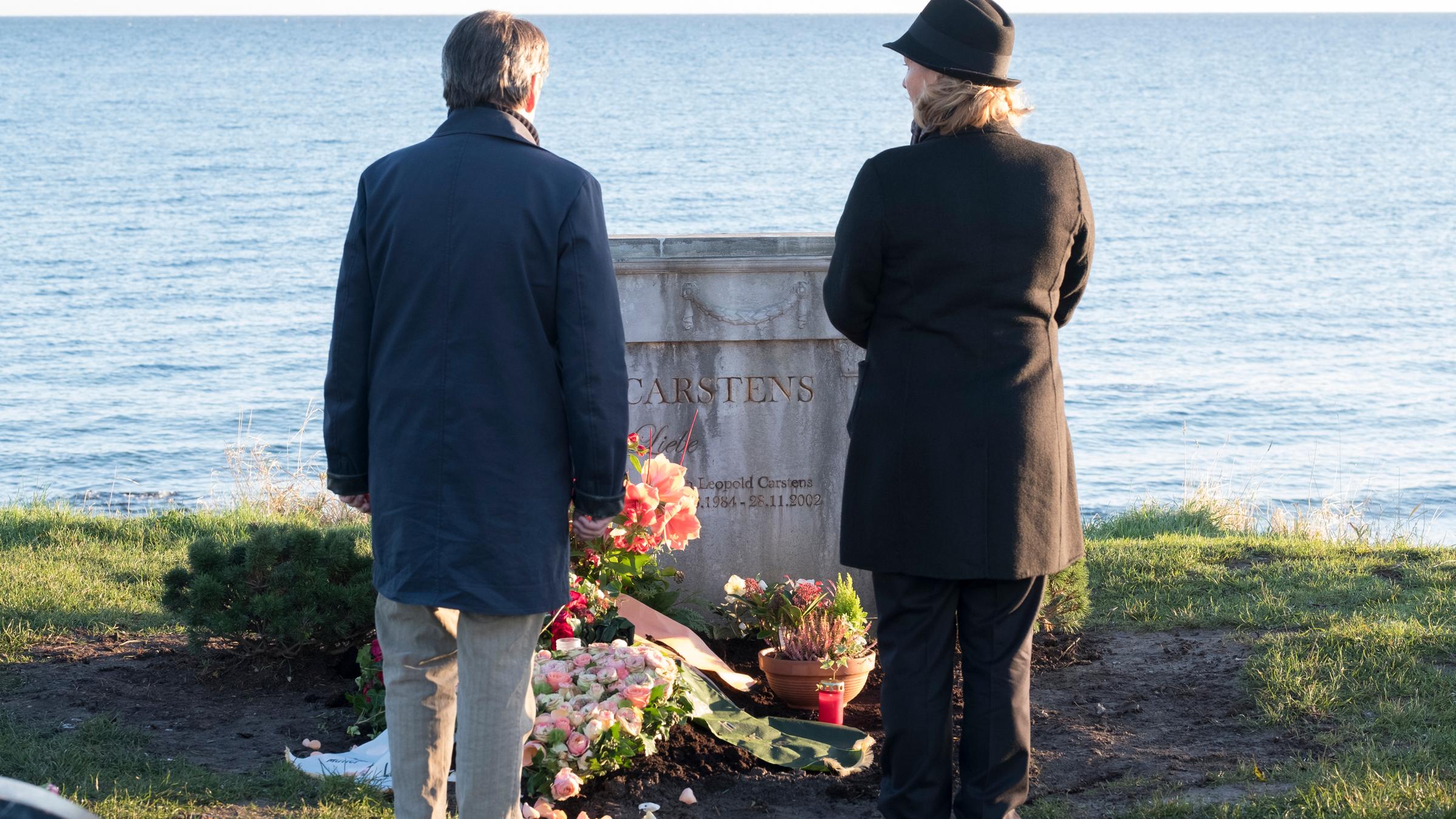 "So weit das Meer": Wolf Harms (Uwe Kockisch) und Uta Carstens (Suzanne von Borsody) stehen vor einem mit Blumen geschmückten Grab, das auf einem Hügel oberhalb des Meeres liegt.