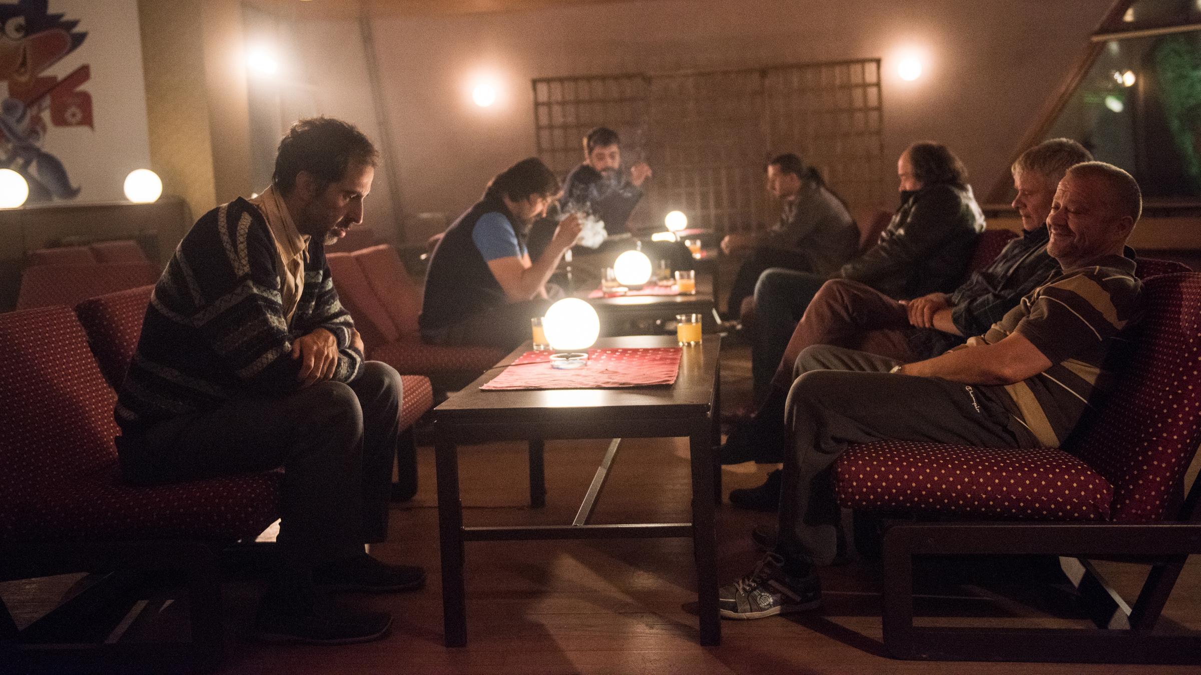 "Männer weinen nicht": Mehrere Männer sitzen und feiern in einer Hotellobby.