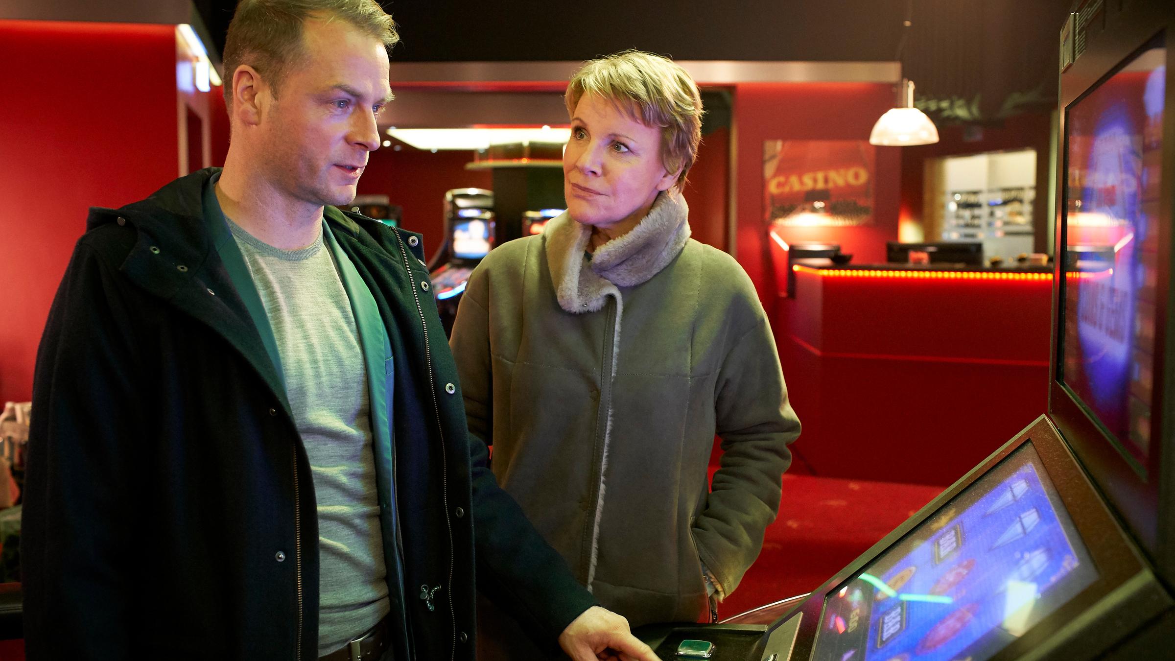 "Marie Brand und das Spiel mit dem Glück": Die beiden Kommissare stehen vor einem Spielautomaten im Spielcasino. Jürgen Simmel bedient den Automaten und Marie Brand schaut ihn verwundert an.