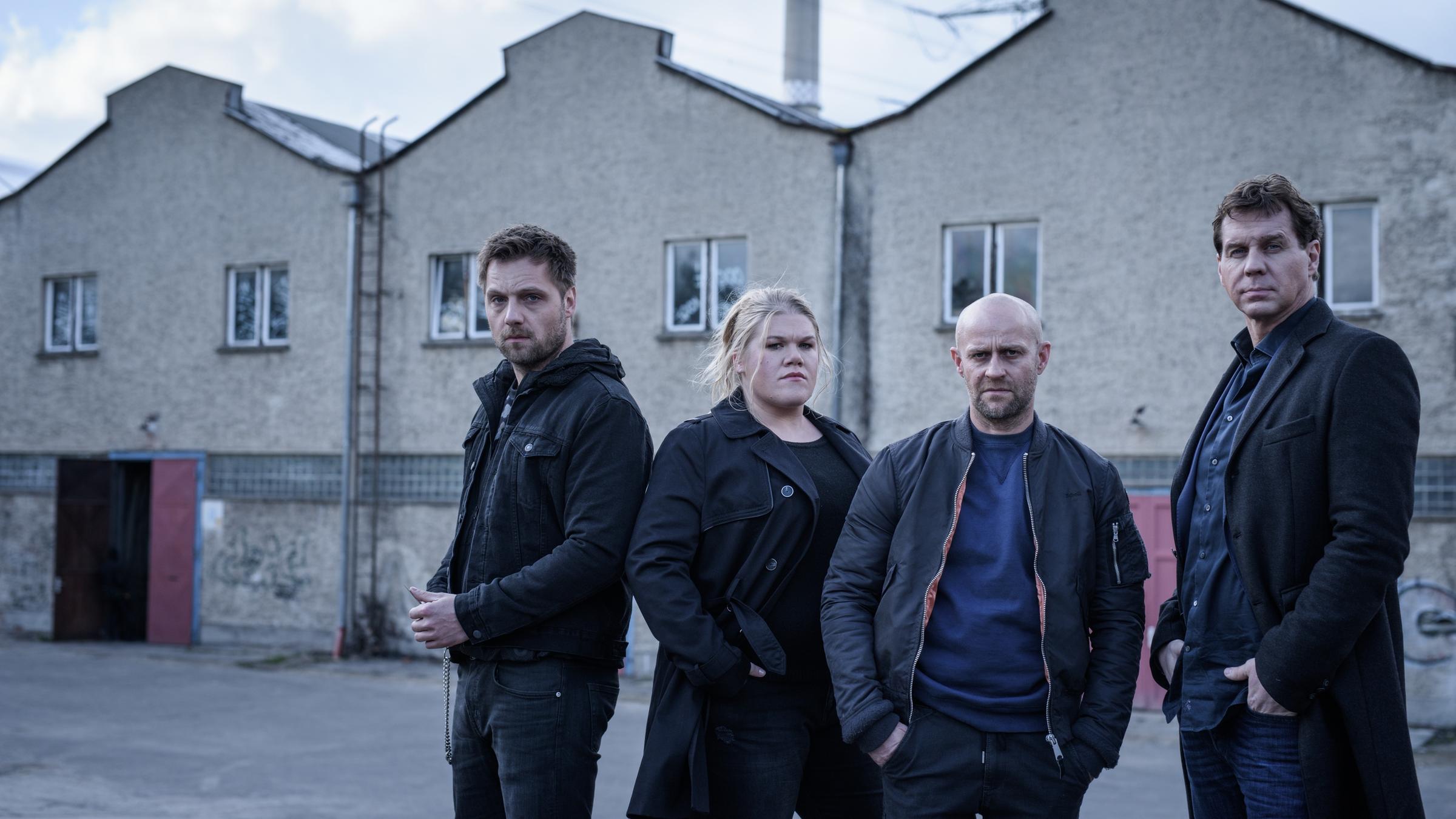 "Blochin - Das letzte Kapitel": Blochin (Jürgen Vogel), Dominik (Thomas Heinze), Yorik (Christoph Letkowski) und Nanette (Gisa Flake) stehen in einer Reihe vor den großen Hallen eines Werkstattgebäudes.