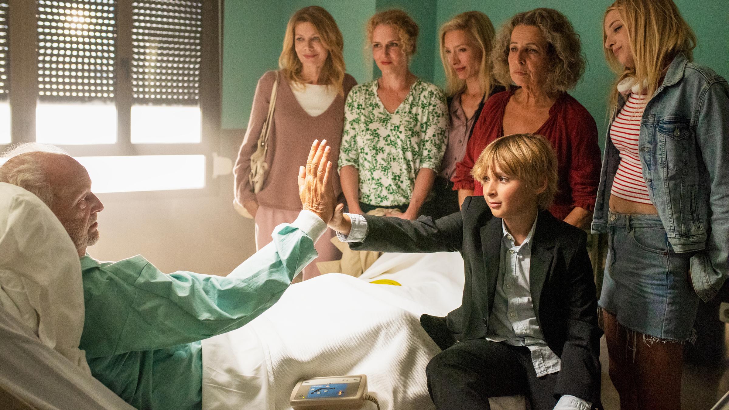 "So einfach stirbt man nicht": Kurt (Michael Gwisdek) liegt im Krankenhausbett und hat Familienbesuch. Seine Frau Renate (Michaela May), seine Töchter Lotte (Ursula Karven), Steffi (Anja Schiffel) und Rebecca (Sandra Borgmann) sowie seine Enkelin Jule (Laetitia Adrian) stehen am Fußende, während der Junge Jonas (Jude West) auf dem Bett sitzt und High Five mit Kurt macht.