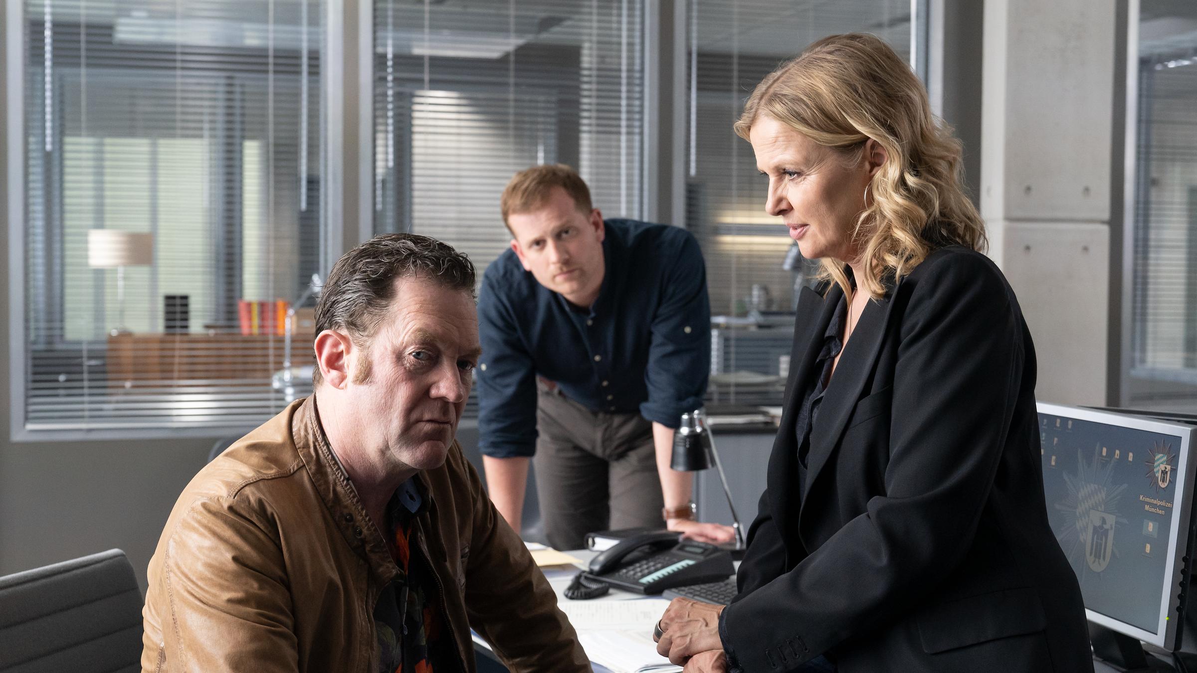 Die Chefin - Justitias Zuhälter“: Vera Lanz (Katharina Böhm) sitzt auf der Tischkante Paul Böhmer (Jürgen Tonkel) gegenüber. Maximilian Murnau (Christoph Schechinger) stützt sich zwischen den beiden auf dem Tisch auf.