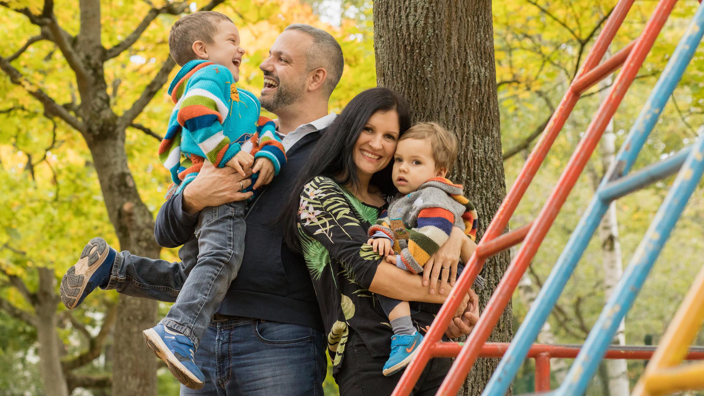 "ZDFzeit: Wo leben Familien am besten? Die große Deutschland-Studie": Familie Gissel steht auf einem Spielplatz. Vater Sascha hält Emil auf dem Arm, die beiden lachen sich an. Jenniffer trägt Finn, die beiden schauen in die Kamera.