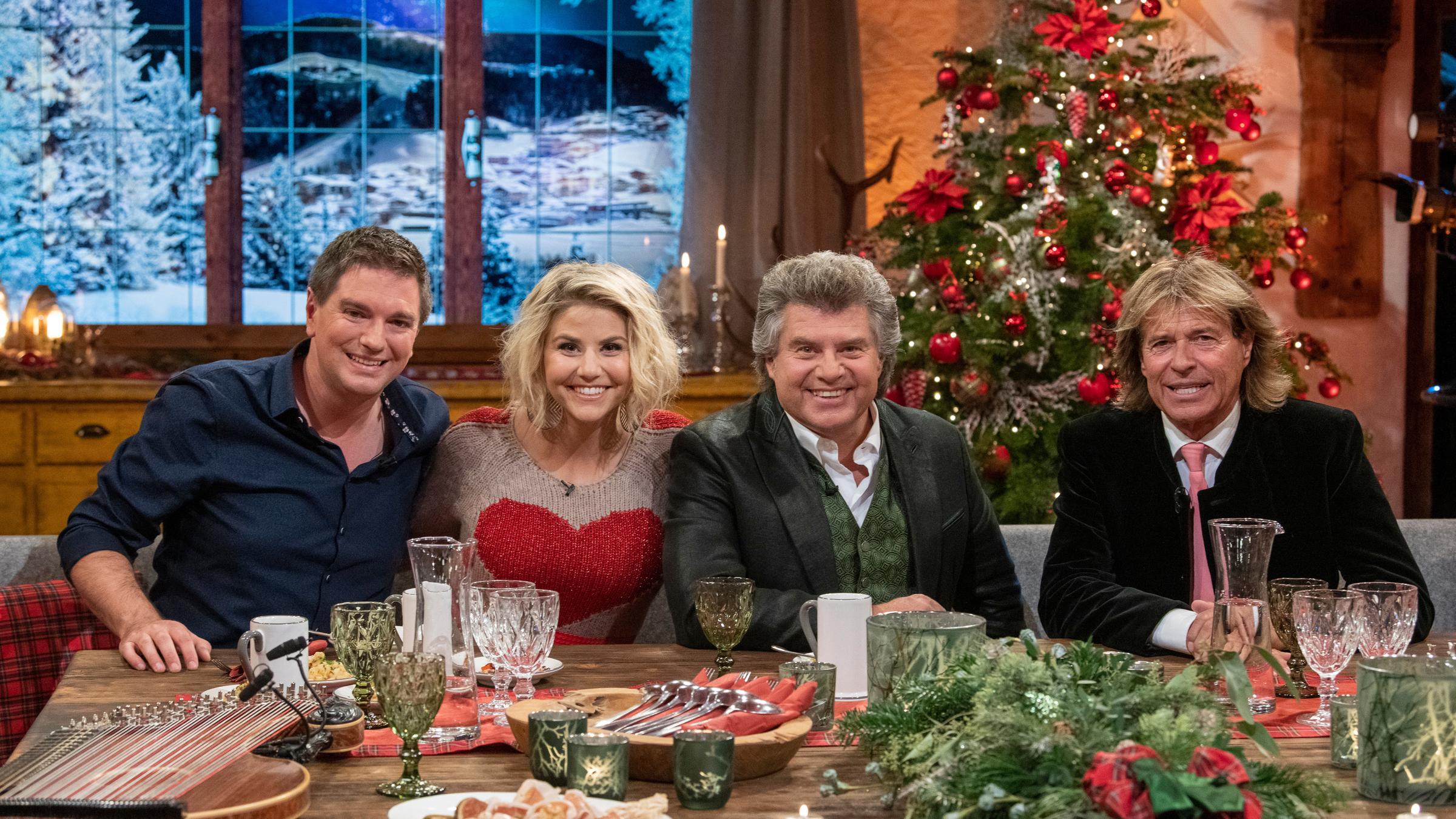 "Heiligabend mit Carmen Nebel": Andreas Erber, Beatrice Egli, Andy Borg und Hansi Hinterseer sitzen an einem weihnachtlich gedeckten Tisch und lächeln in die Kamera.