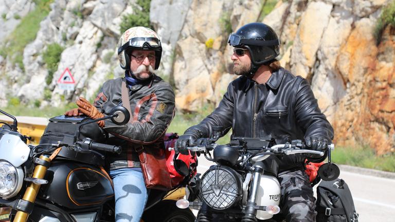 "Horst Lichter sucht das Glück - Mit dem Motorrad durch Kroatien": Horst Lichter und Henning Baum sitzen auf ihren Motorrädern. Sie schauen sich an und haben beide ihre Motorradhelme auf. Im Hintergrund sieht man Felsen.