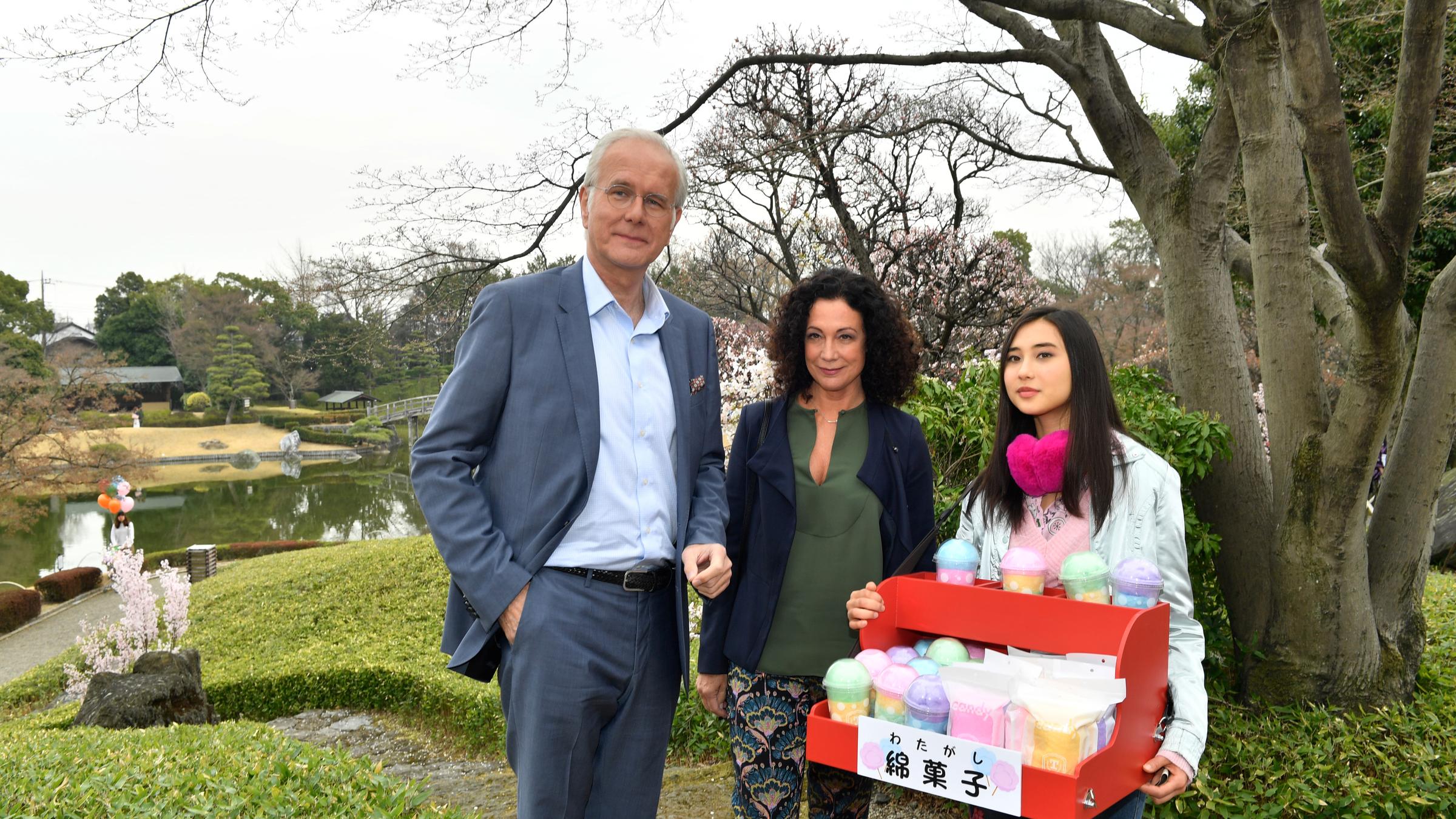 "Das Traumschiff: Japan": Miko (Julia Strowski) steht mit einem Bauchladen im Park. Neben ihr stehen Hanna Liebhold (Barbara Wussow) und Oskar Schifferle (Harald Schmidt).