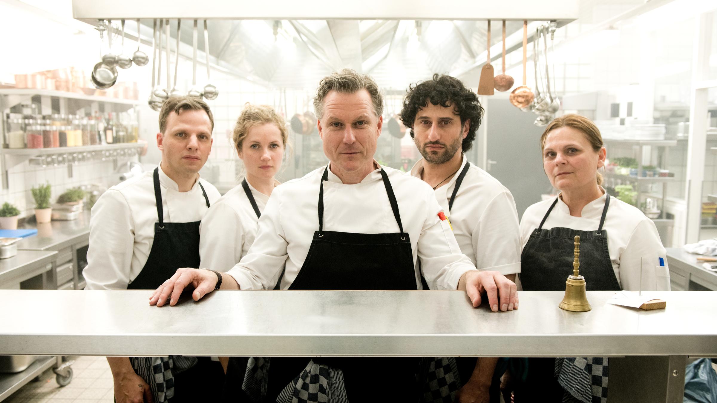 "Mord geht immer - Der Koch ist tot": Jan Remus (Peter Miklusz), Julia Kindt (Cornelia Gröschel), Peter Grünweg (Dirk Borchardt), Thomas Ross (Serkan Kaya) und Olga Porizkova (Zeljka Preksavec) stehen hinter der Essensausgabe der Küche und schauen in die Kamera.