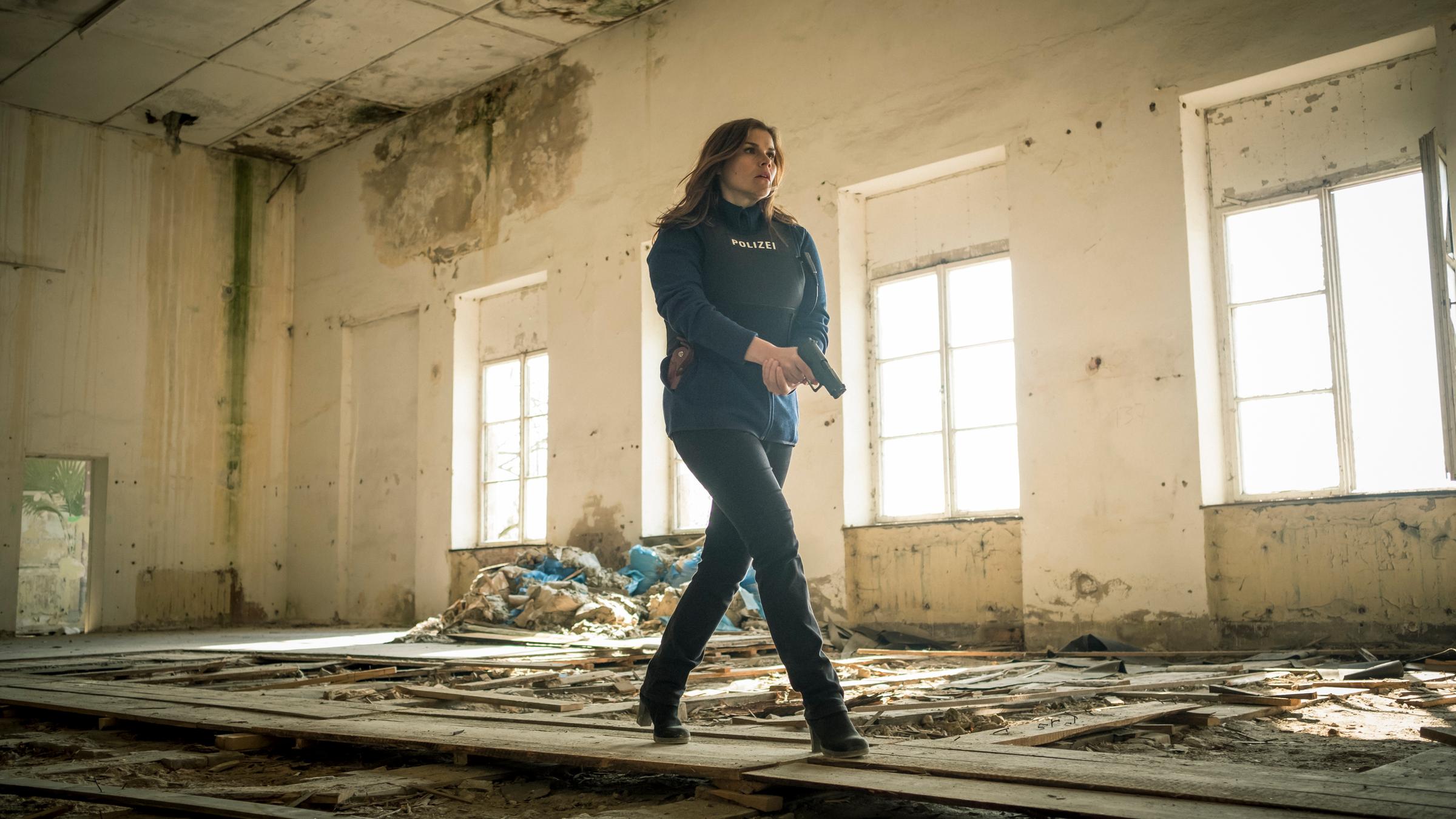 "Stralsund - Schattenlinien": Nina Petersen (Katharina Wackernagel) geht mit gezogener Pistole und schusssicherer Weste durch einen völlig entkernten Raum.