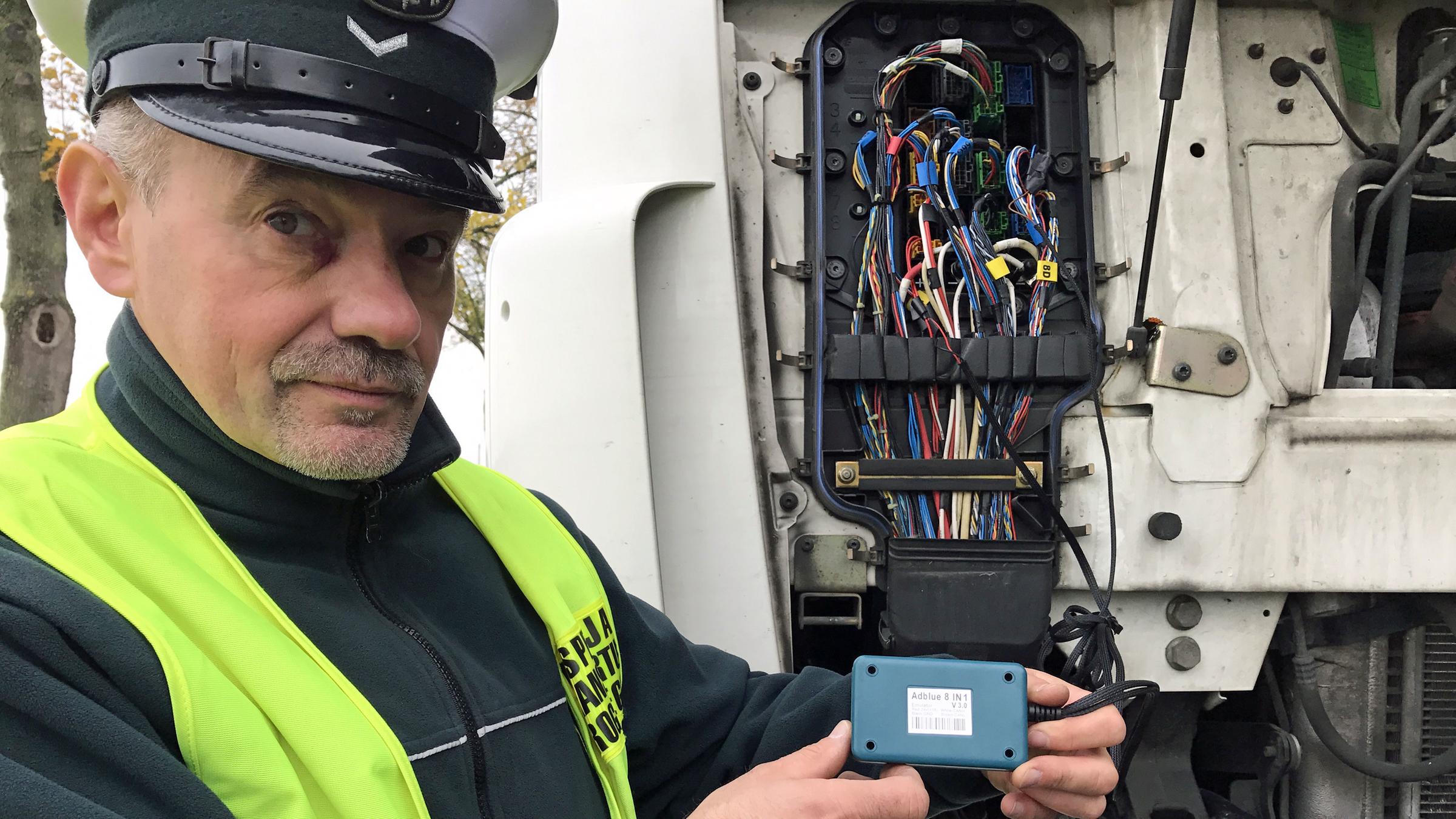 "ZDFzoom: Die Lüge vom sauberen LKW - Abgas-Betrüger und ihre Dreckschleudern": Polnischer Polizist hält einen AdBlue-Emulator in die Kamera.