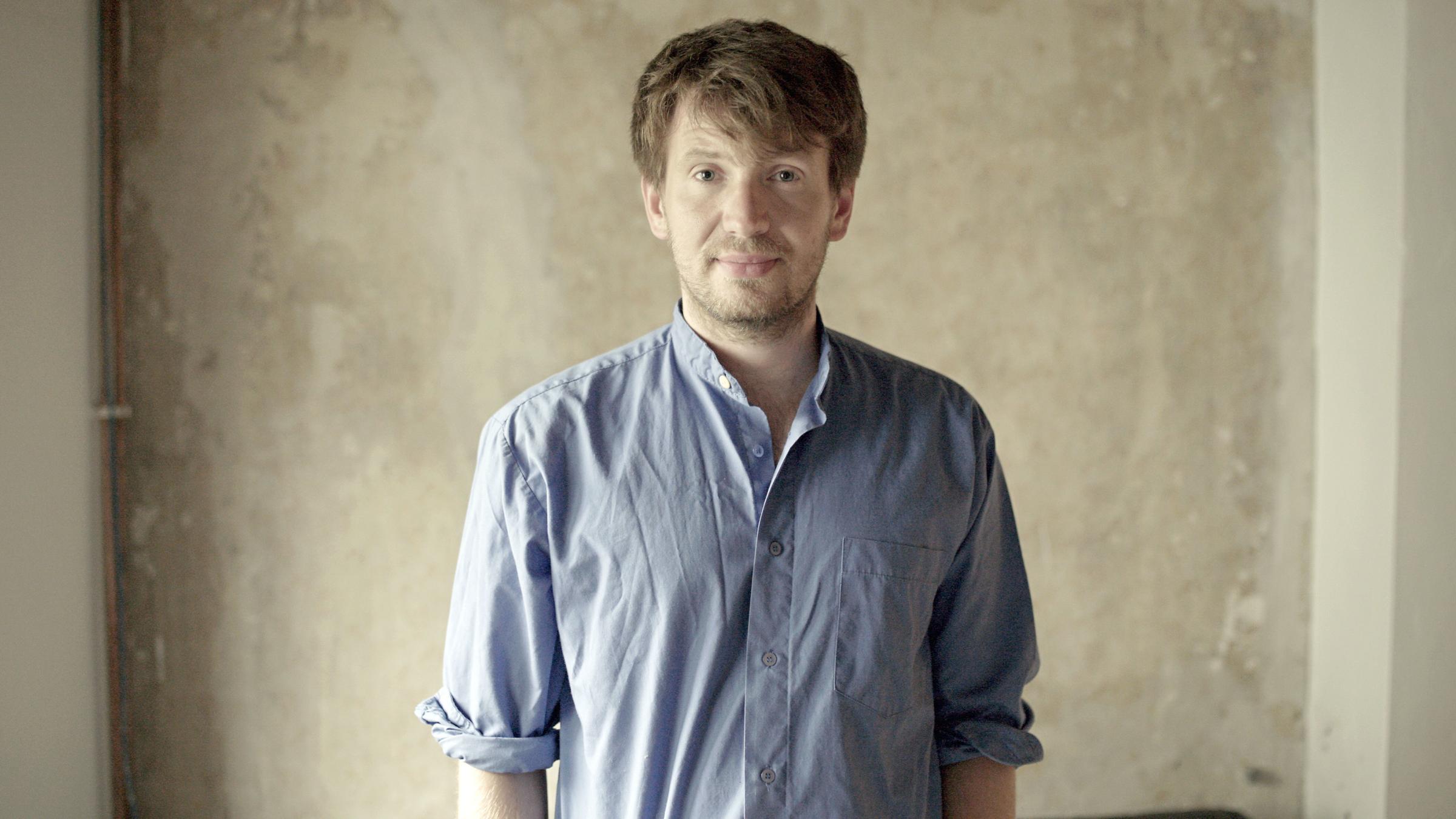  "Meschugge oder was - Jude werden, Jude sein in Deutschland": Dmitrij Kapitelman steht vor einer Wand und schaut in die Kamera.