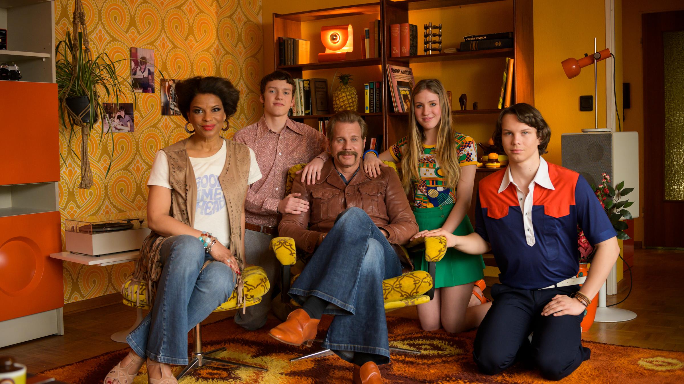 "Grüße aus 1976 - Auf Zeitreise mit Thomas Heinze": Familie Heinze mit Jackie Brown, Lennon, Thomas Heinze, Lucille und Sam sitzen in einem typischen Wohnzimmer des Jahres 1976.