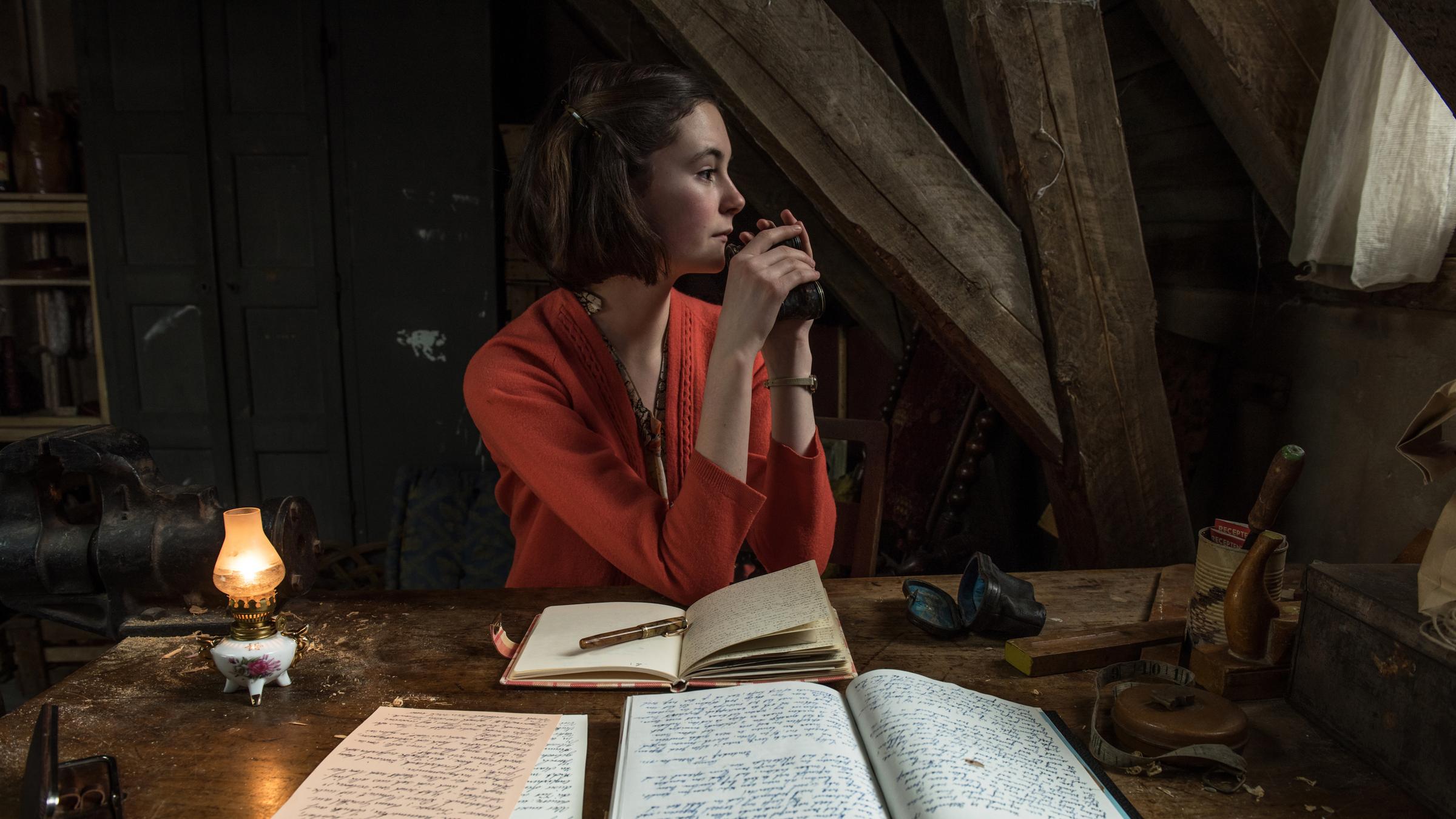 "Das Tagebuch der Anne Frank": Anne Frank (Lea van Acken) sitzt an einem Tisch und sieht zur Seite. Vor ihr liegt ihr Tagebuch