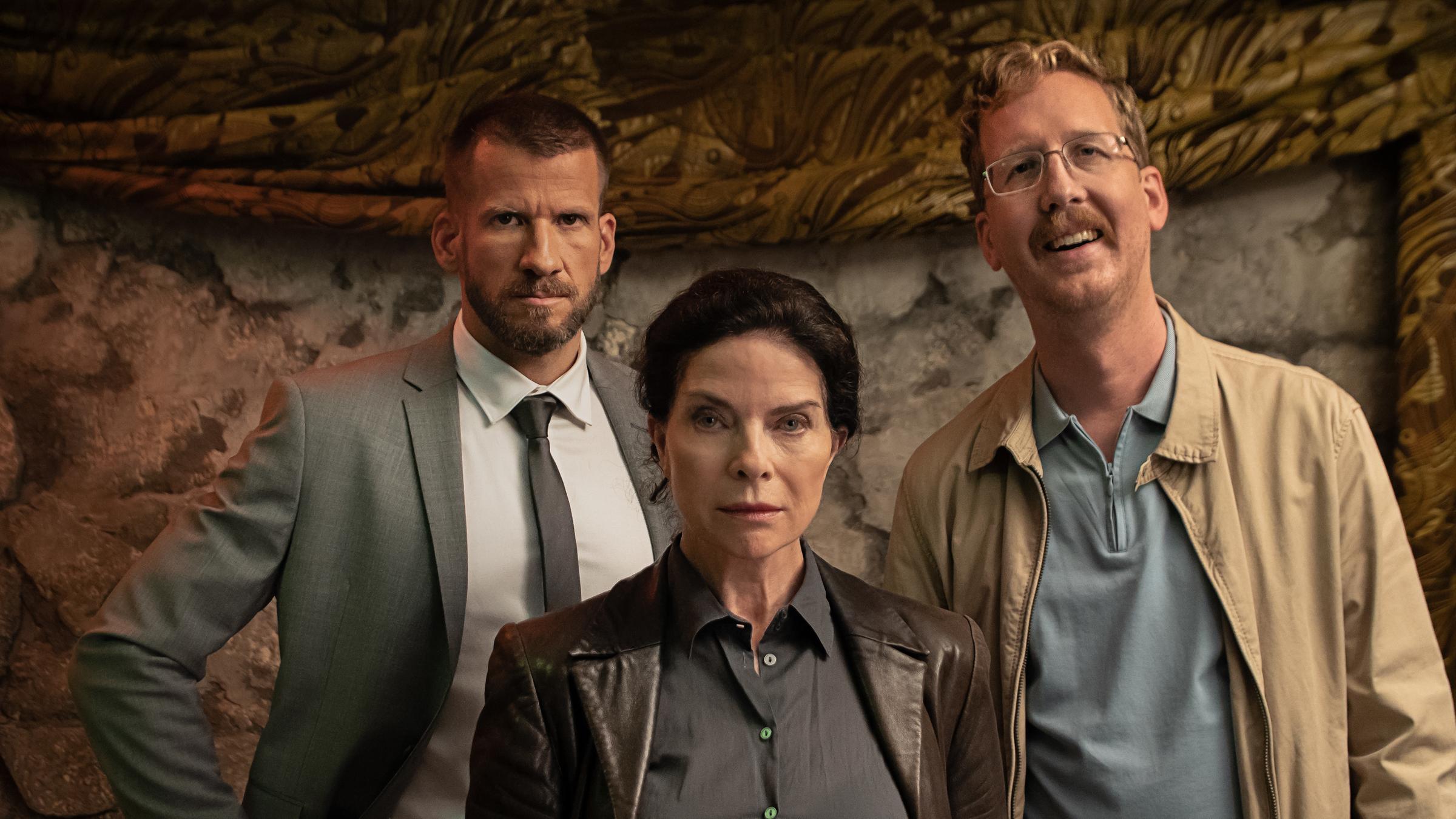 "In bester Verfassung": Matthias Frings (Fabian Siegismund), Paul Horner (Uke Bosse) und Mechthild Dombrowski (Gudrun Landgrebe) stehen in einer Nahaufnahme vor einer Steinwand.