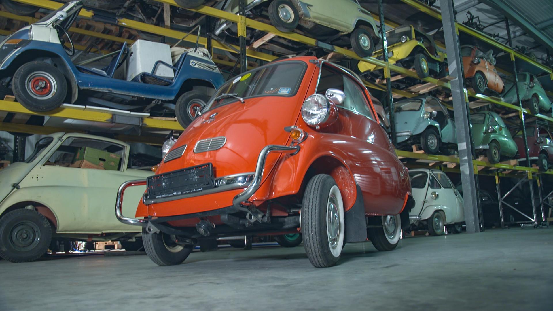 "Bella Germania - Die Dokumentation": BMW Isetta in einer Halle. Im Hintergrund in einem Hochregal weitere Fahrzeuger dieses Typs.