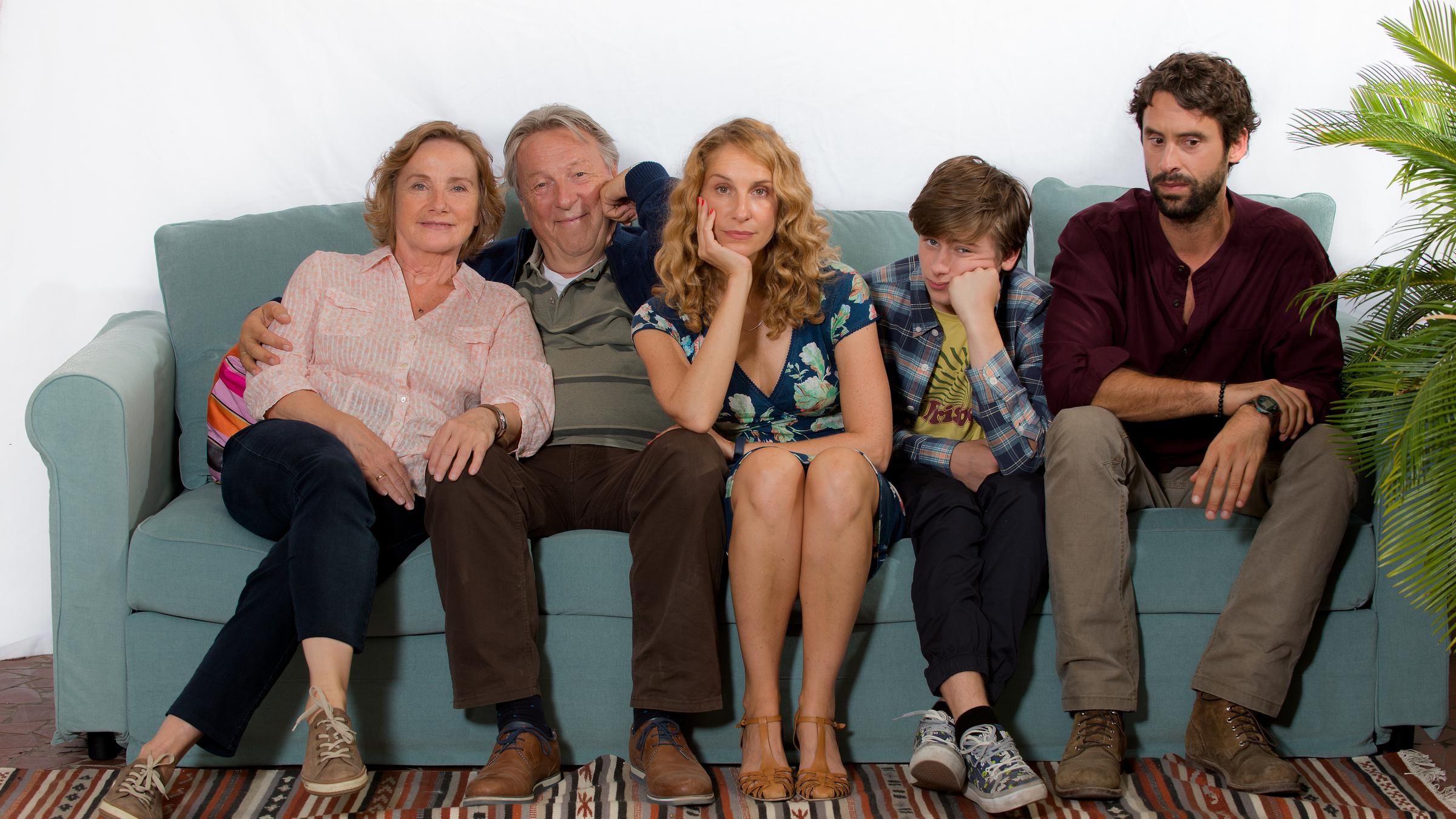 "Mit der Tür ins Haus": Auf einer Couch sitzen: Noras Eltern Hanne Kaffenberg (Ruth Reinecke) und Wolfgang Kaffenberg (Hansjürgen Hürrig), Nora Jacob (Chiara Schoras), ihr Sohn Linus Jacob (Paul Sundheim) und Khalid Naybet (Kai Albrecht). Nora und Linus haben die Köpfe auf eine Hand gestützt und blicken etwas ratlos.
