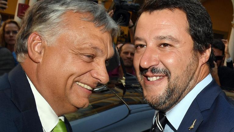 ZDFzeit: Laut, forsch, national - Wie Salvini, Orbán & Co. Europa spalten": Victor Orbán und matteo Salvini  lachen und stehen dabei vor einem dunklen Auto. Im Hintergrund Presseleute.