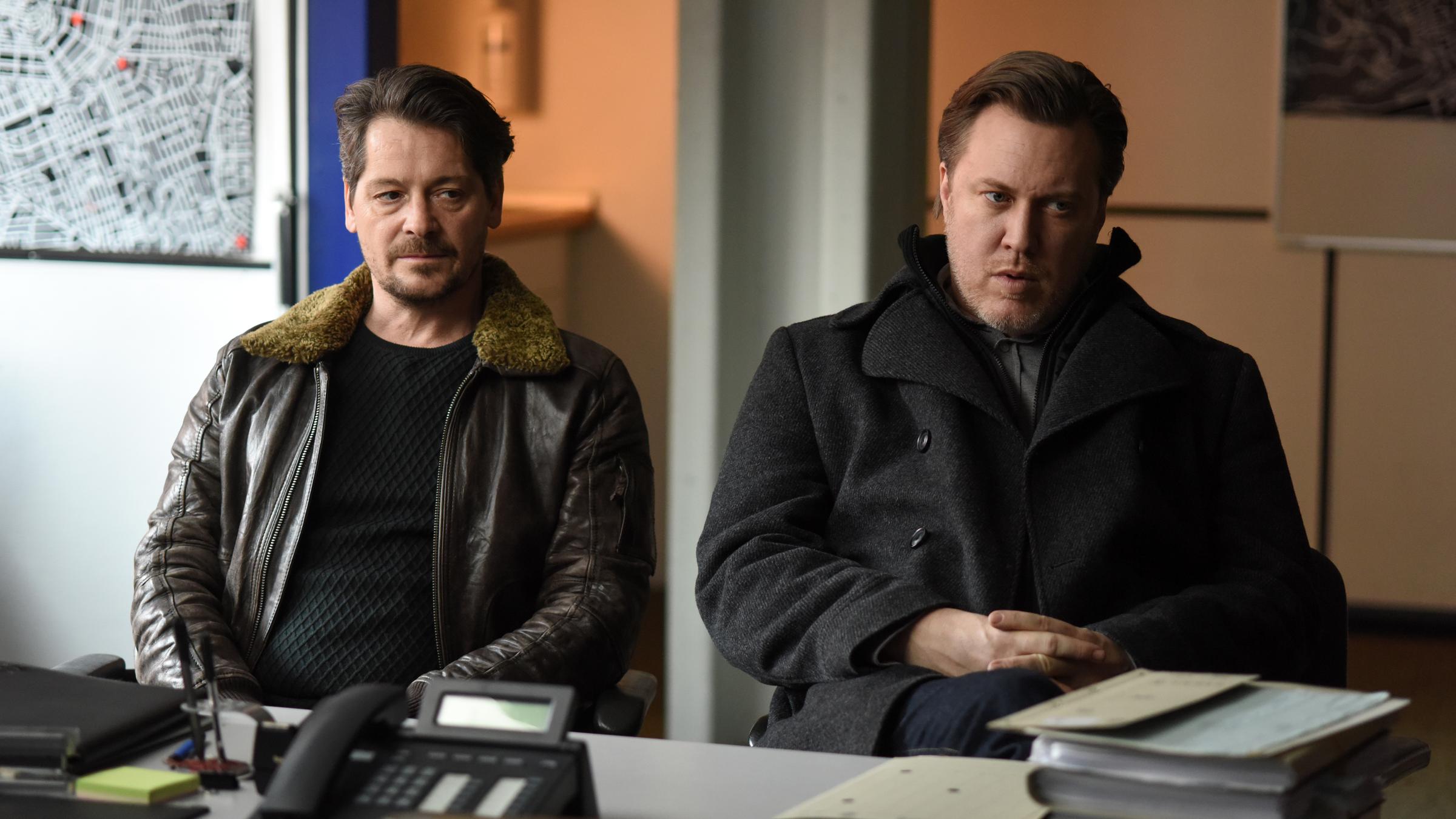 "Reich oder tot": Kessel (Fritz Karl)  und Diller (Nicholas Ofczarek) sitzen nebeneinander vor einem Schreibtisch und schauen etwas gelangweilt drein.