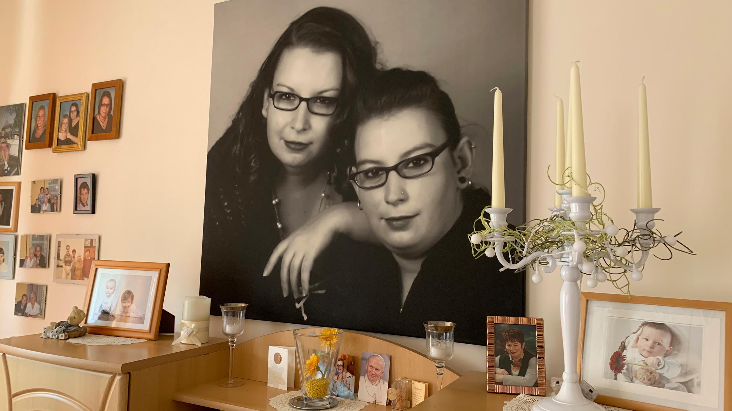 "37°: Vermisst - Wenn Menschen spurlos verschwinden": Leinwand im Wohnzimmer der Eltern der vermissten Anna. Das Bild zeigt die Vermisste sowie ihre Zwillingsschwester Edith in Schwarzweiß. Davor diverse Kerzen und weitere Bilderrahmen.