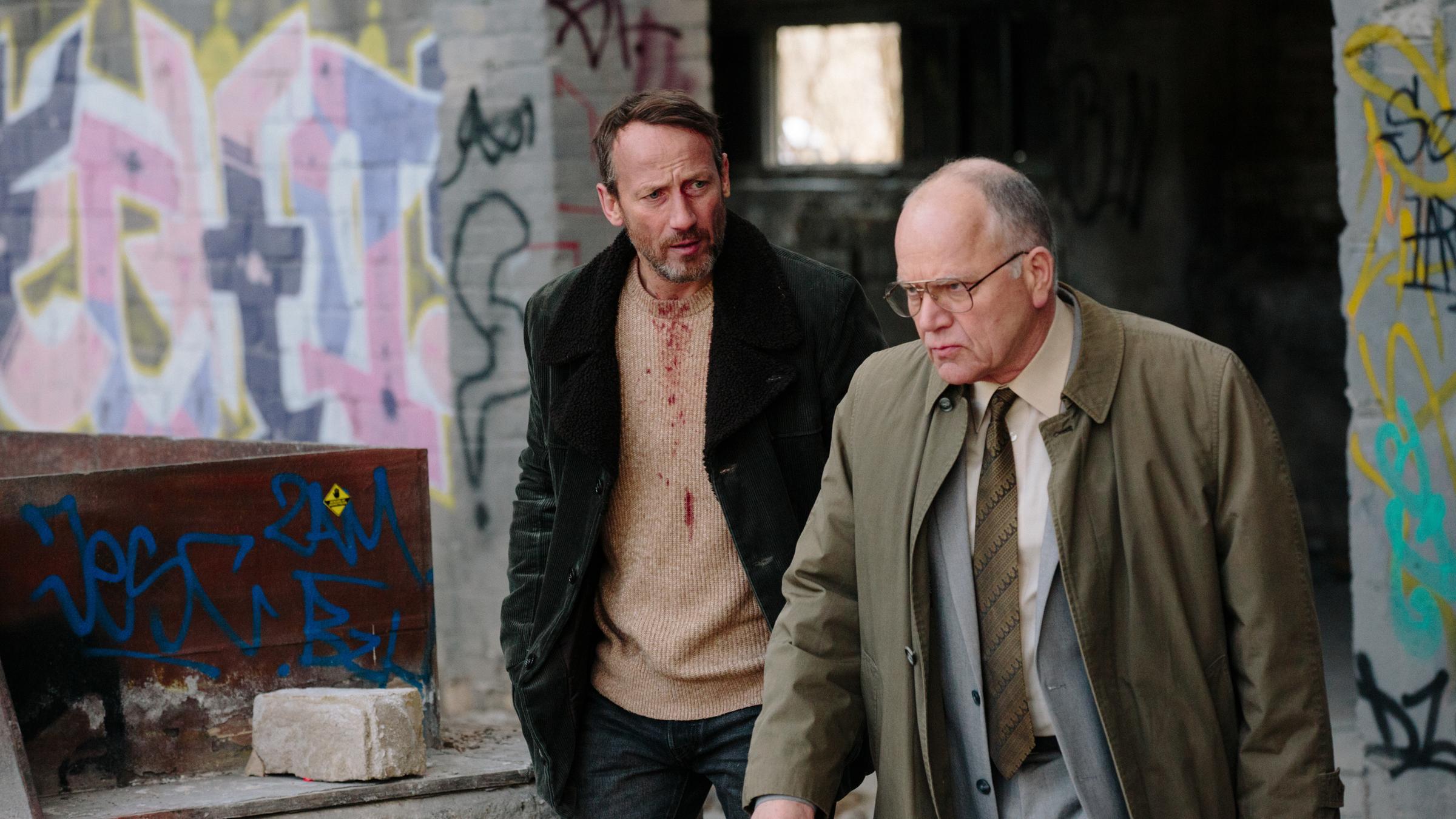 "West of Liberty: Folge 1": GT Berner (Matthew Marsh) und Ludwig Licht (Wotan Wolke Möhring) gehen durch eine Fabrikruine und unterhalten sich.