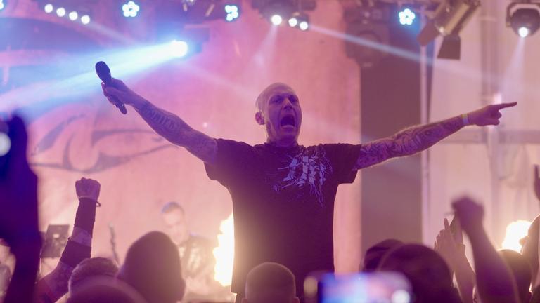 "Rechtsrock in Deutschland - Das Netzwerk der Neo-Nazis": Der Sänger einer rechtsradikalen Band steht mit ausgestreckten Armen auf der Bühne und schreit ins Publikum.