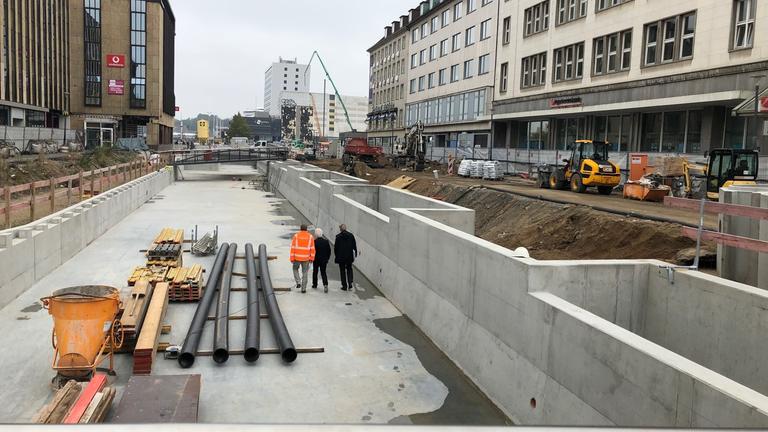 "plan b - Lasst die Städte leben!": Bauarbeiter gehen über die Baustelle des "Kleine Kiel-Kanals" in der Kieler Innenstadt.