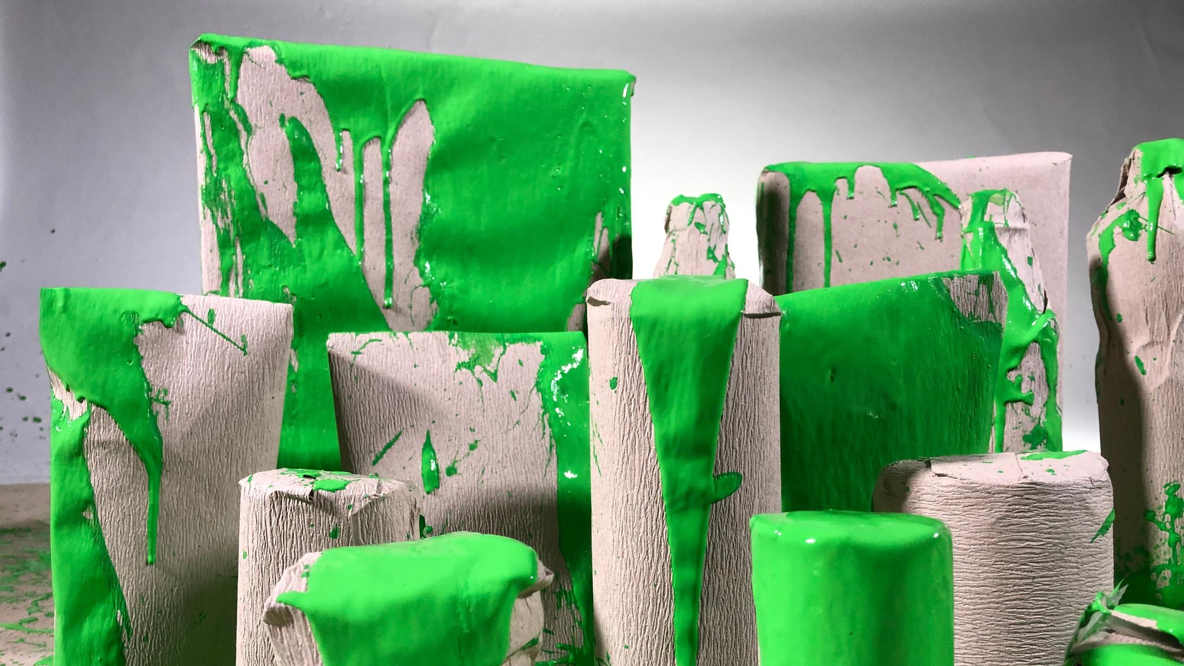 "Grüne Versprechen - Wie Verbraucher getäuscht werden": Blick auf selbst gemachte Verpackungen, die mit grüner Farbe beschmiert sind.