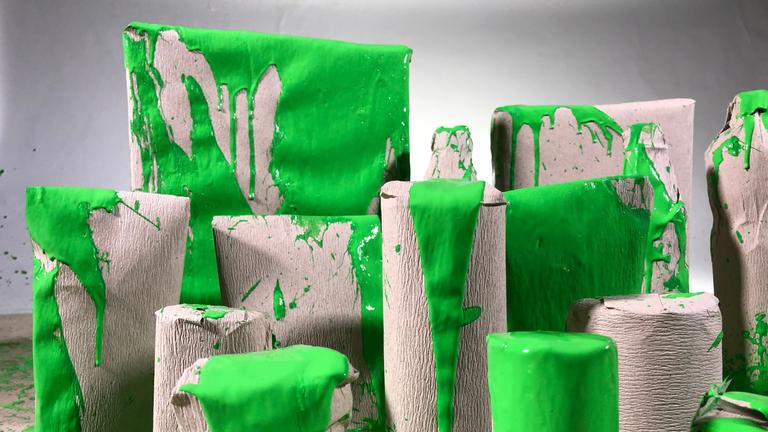 "Grüne Versprechen - Wie Verbraucher getäuscht werden": Blick auf selbst gemachte Verpackungen, die mit grüner Farbe beschmiert sind.