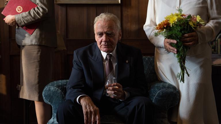 "In Zeiten des abnehmenden Lichts": Wilhelm Powileit (Bruno Ganz) sitzt im schicken Anzug auf einem Sessel, mit einem Getränk in der Hand.