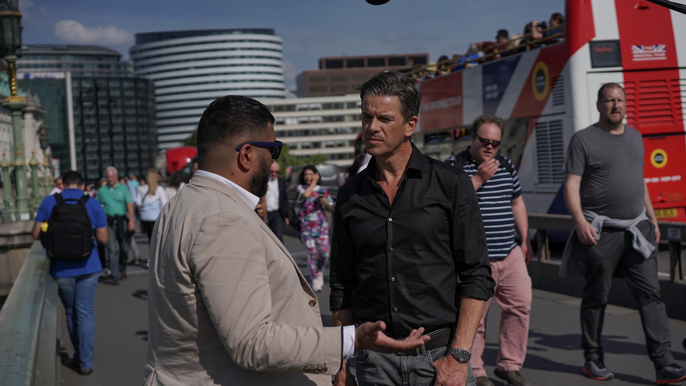 "Markus Lanz - England ungeschminkt" Markus Lanz im Gespräch mit einem Bürger auf der Westminster Brücke. Um sie herum sind Passanten und Busse unterwegs.