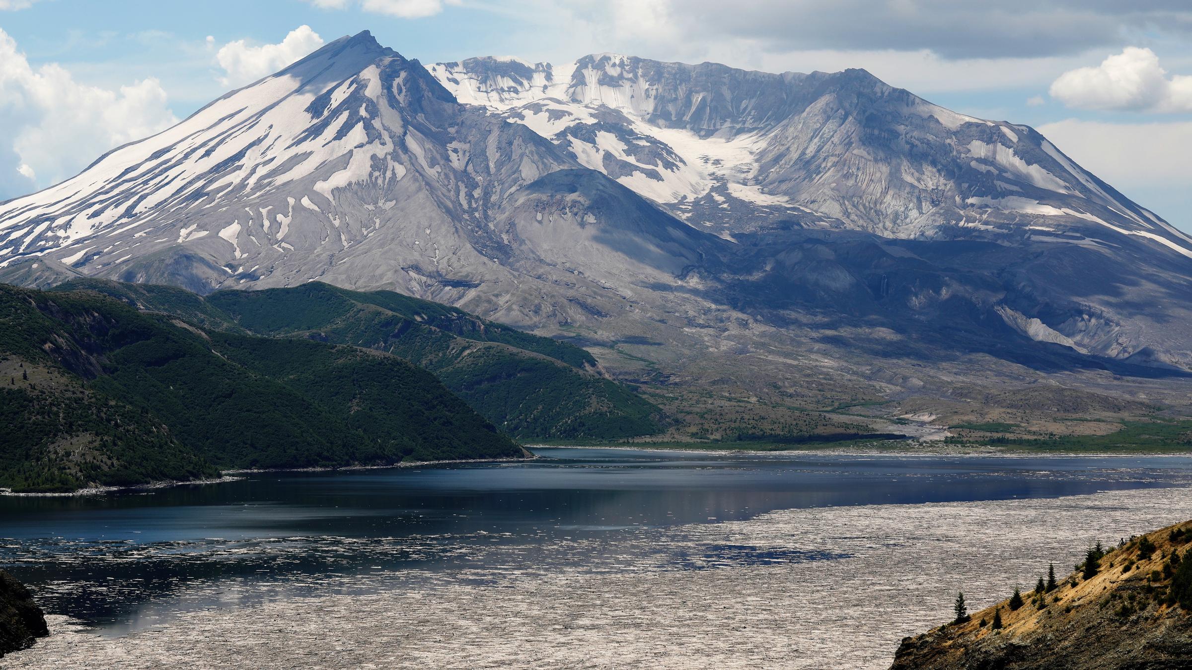 "Terra X: Feuer und Eis": Großer Berg mit stadionförmigem Krater, teils schneebedeckt. Im Vordergrund liegt ein See, in dem Baumstämme schwimmen.