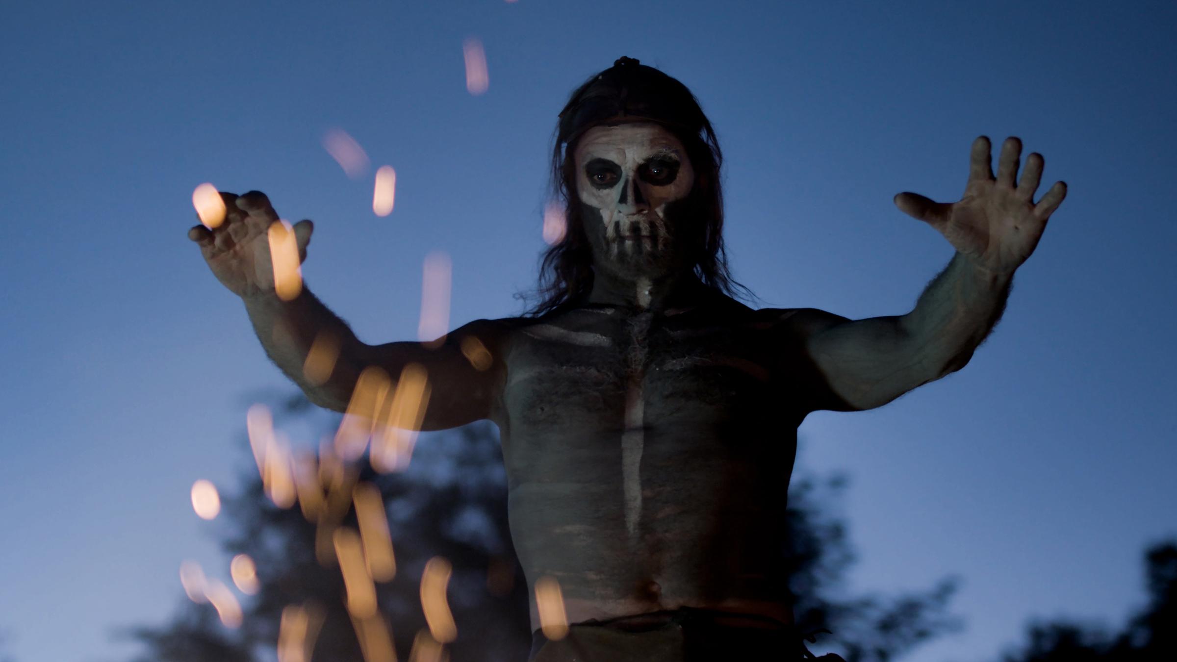 "Terra X: Tatort Steinzeit - Deutschland vor 7000 Jahren": Spielszene: Bemalter Krieger steht vor Feuer und breitet beschwörend die Hände aus.