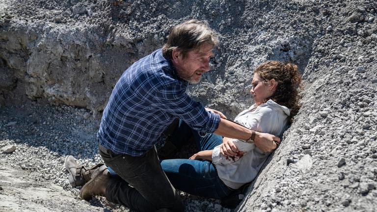 "Die Toten von Salzburg - Wolf im Schafspelz": Außenaufnahme. Hubert Mur (Michael Fitz) und Irene Russmeyer (Fanny Krausz) in einem Graben. Irene liegt verletzt am Boden.