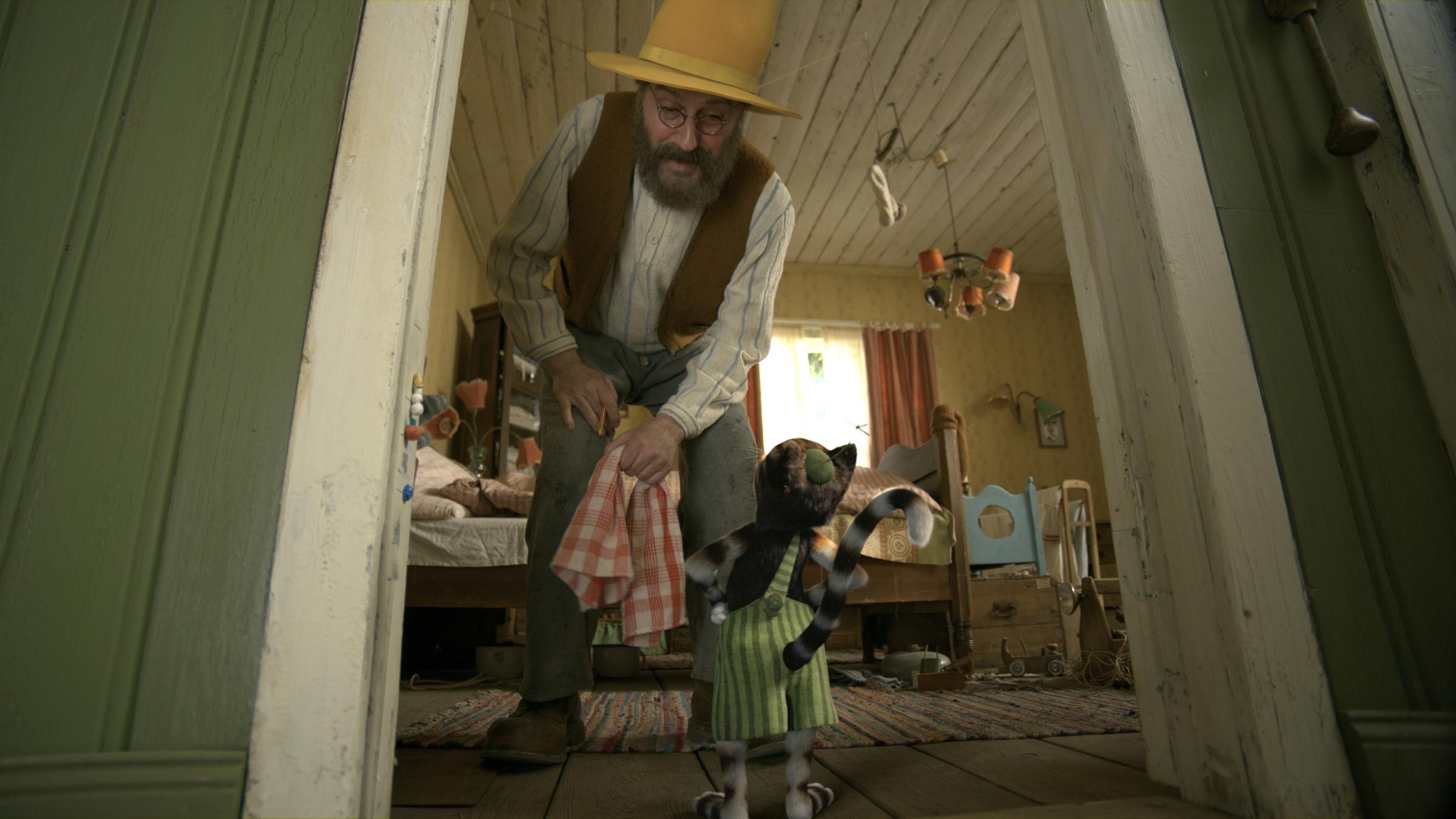 "Pettersson und Findus - Findus zieht um": Das Schlafzimmer von Pettersson. Dort steht Findus mit dem Rücken zur Kamera und blickt hoch zu Pettersson (Stefan Kurt), der sich gerade zu dem kleinen Kater herunterbeugt. Die beiden reden miteinander.