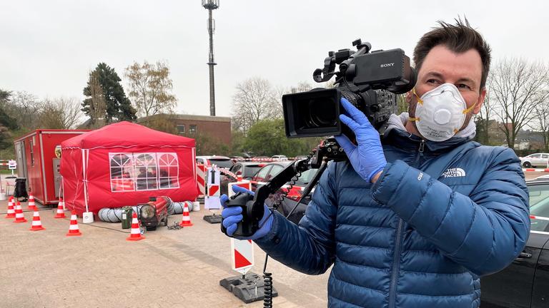 "ZDFzoom: Katastrophenschutz am Limit - Wie gut ist Deutschland aufgestellt?": Kameramann in blauer Jacke mit Atemschutzmaske.