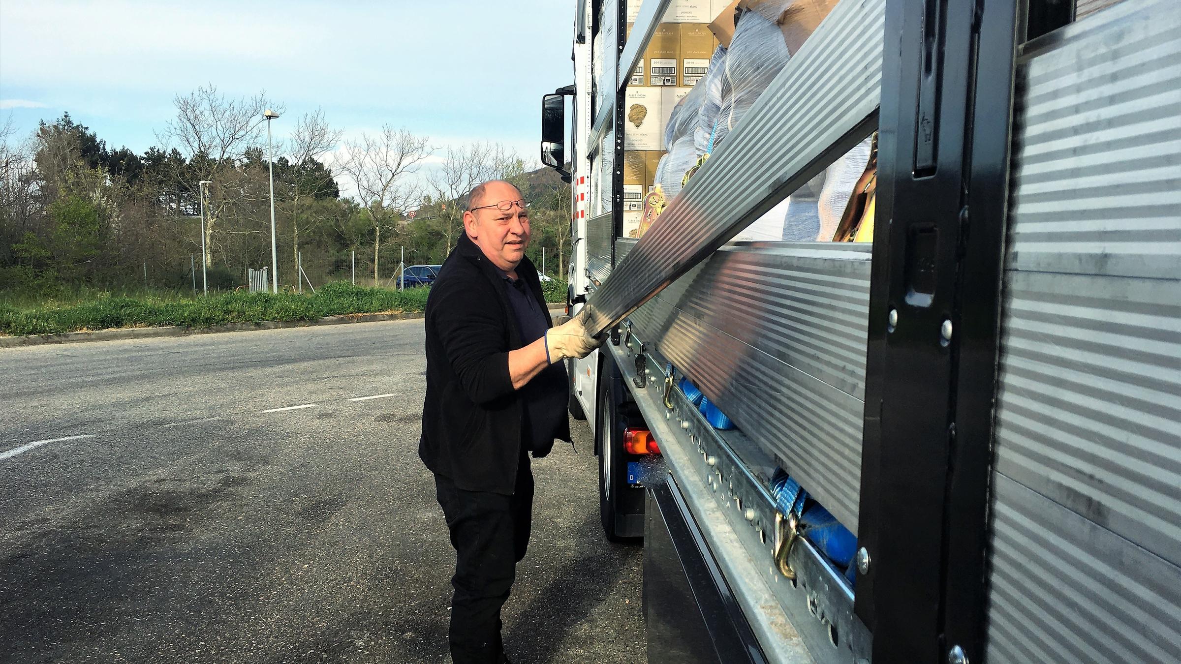 "ZDFzoom: Löchriges Liefernetz": Volkmar Krämer steht auf einem Parkplatz an seinem Lkw und befestigt eine Abdeckung.