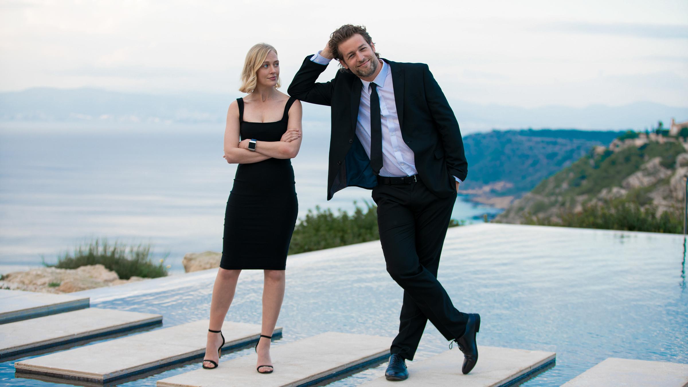 "The Mallorca Files - Sag niemals Goodbye, Compañero": Miranda (Elen Rhys) und Max (Julian Looman) stehen in Abendkleidung auf den Treppen eines Pools.